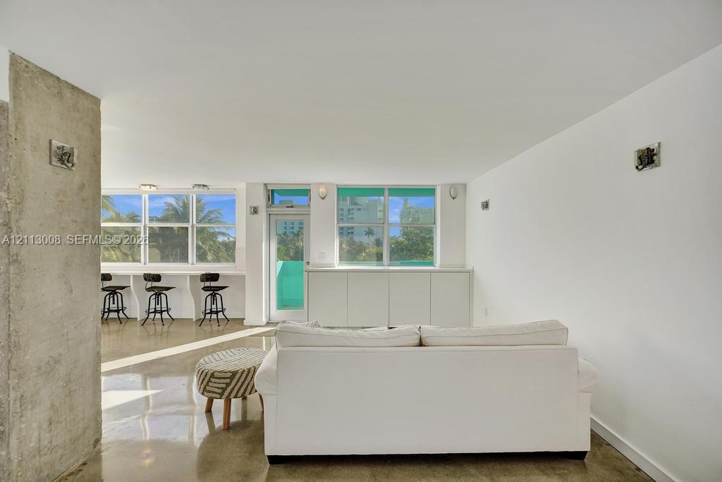 Polished concrete flooring, exposed concrete structural column, built-in lower cabinetry, and expansive windows with glass entry door
