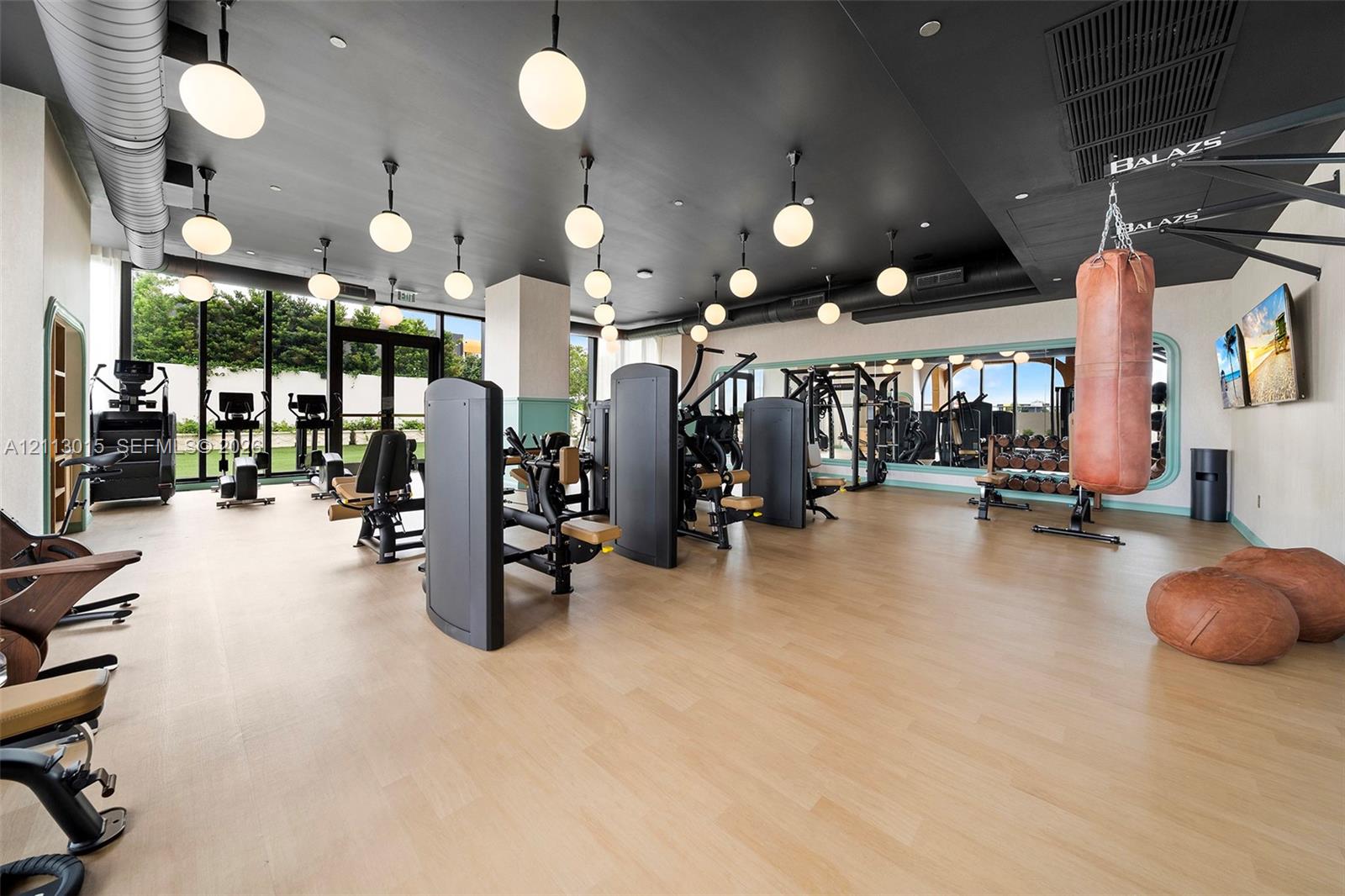 Fitness center featuring wood-finish flooring, floor-to-ceiling windows, recessed and pendant lighting, and a full-length wall mirror