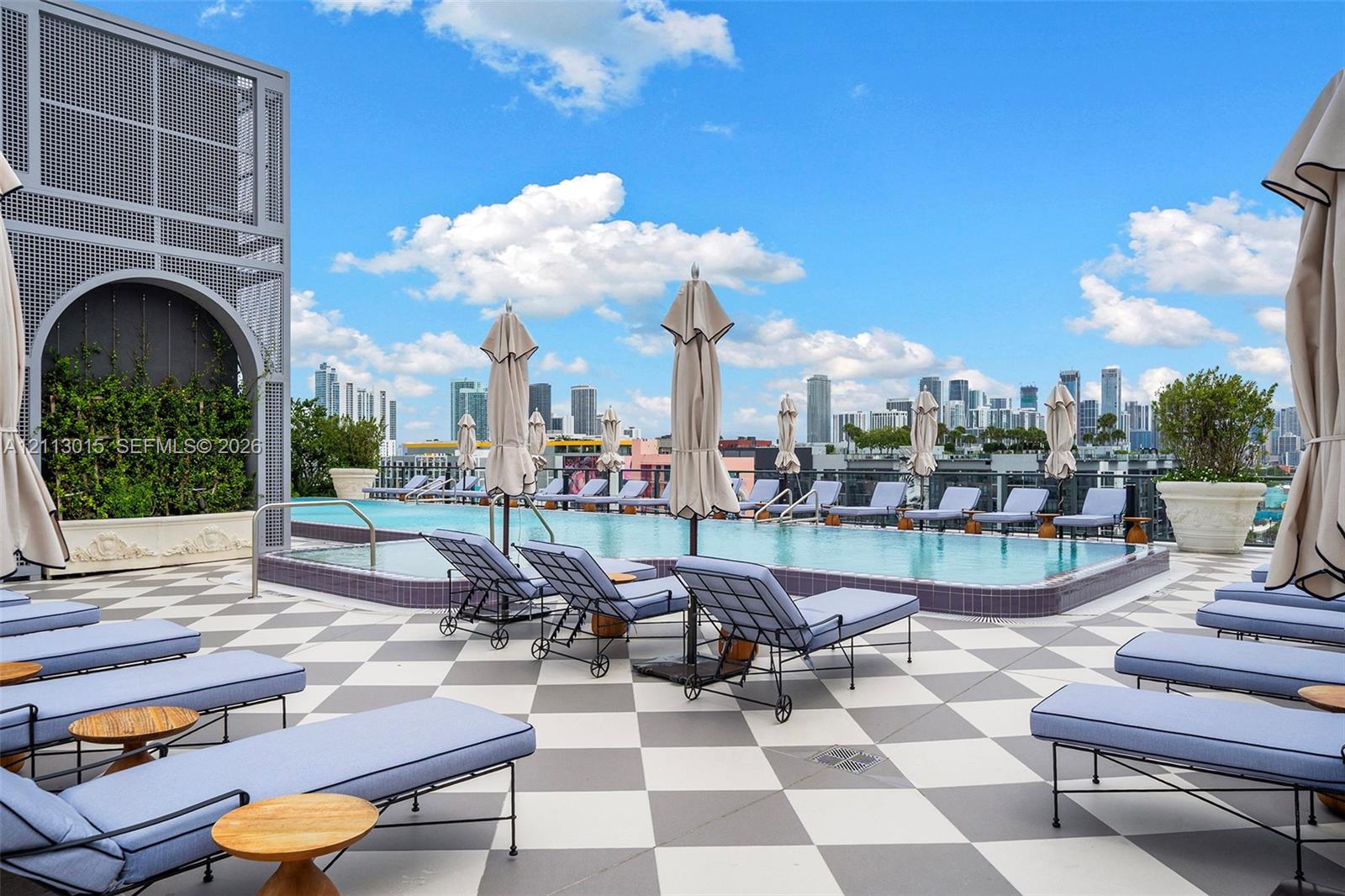 Rooftop infinity-edge pool featuring a geometric tiled deck and large-scale architectural planters
