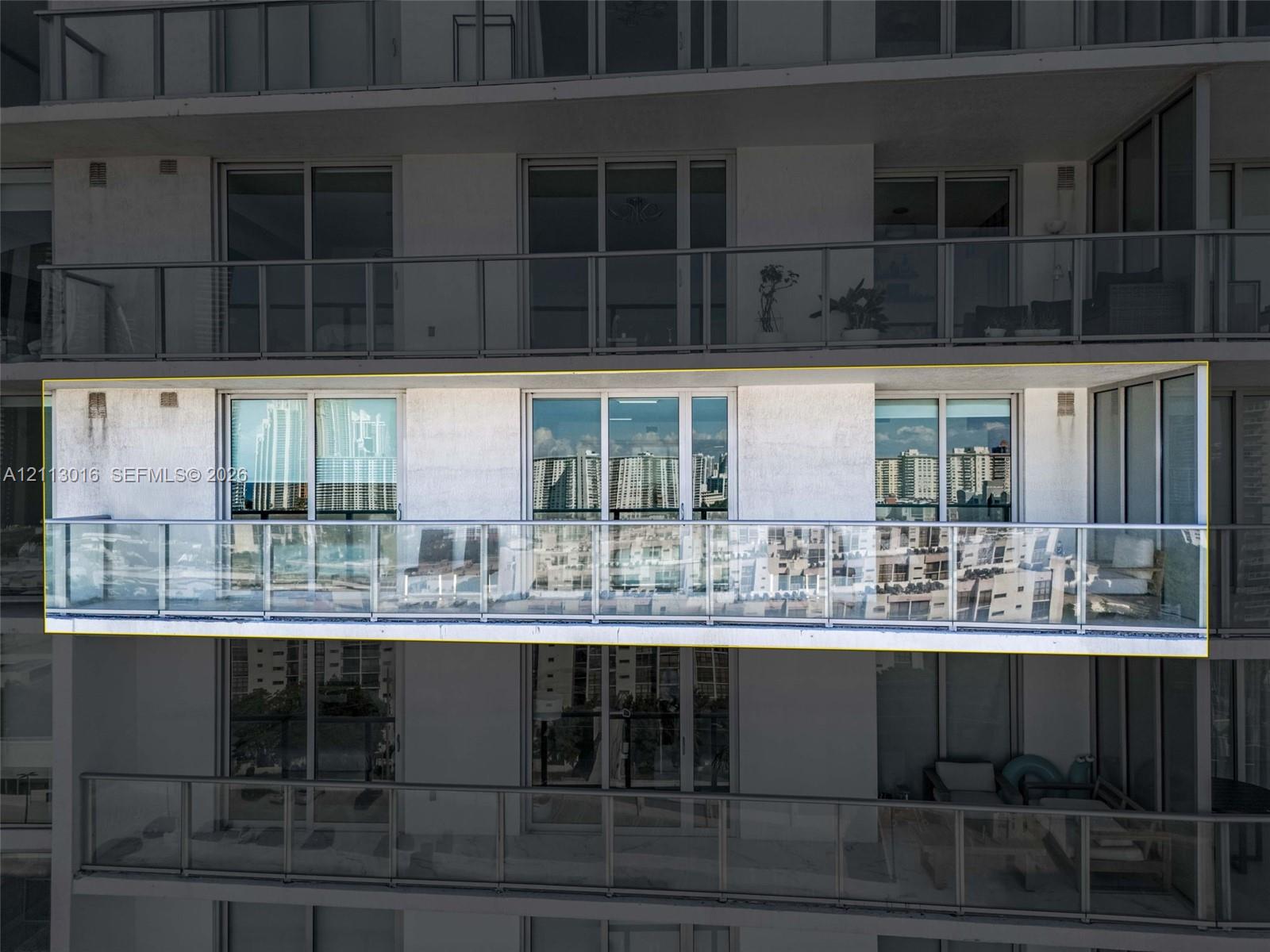 Spacious private balcony featuring a glass panel railing and full-height sliding glass doors