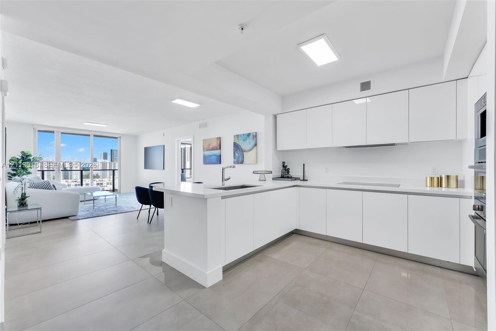 Modern kitchen featuring sleek white cabinetry, a stone-surface countertop, an integrated sink, built-in stainless steel appliances, and large-format tile flooring Modern kitchen featuring sleek white cabinetry, a stone-surface countertop, an integrated sink, built-in stainless steel appliances, and large-format tile flooring