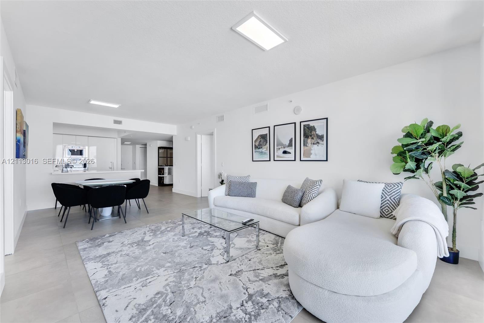 Open-concept interior featuring large-format tile flooring, recessed rectangular lighting fixtures, and clean white walls Open-concept interior featuring large-format tile flooring, recessed rectangular lighting fixtures, and clean white walls