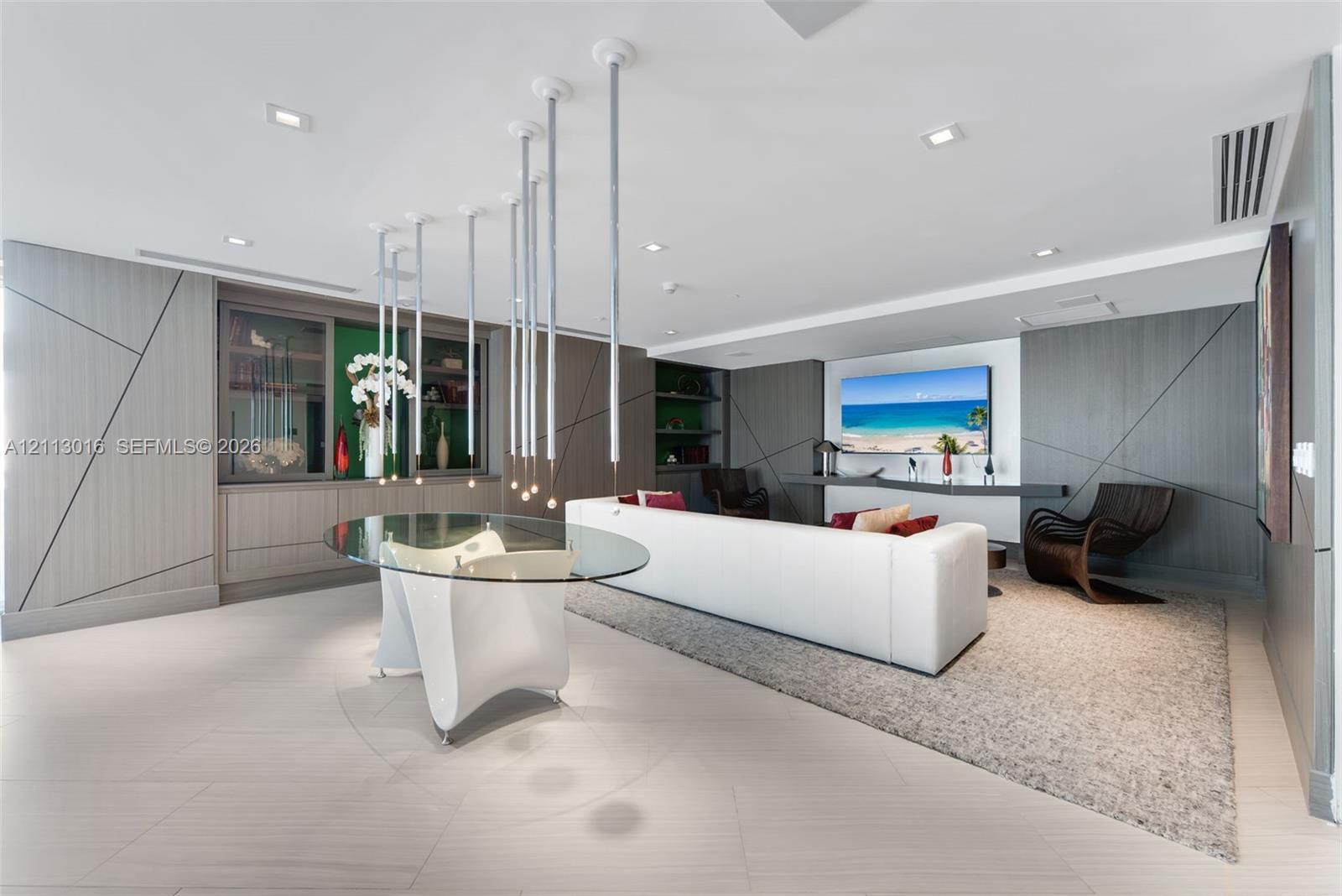 Custom living area featuring geometric wall paneling, built-in cabinetry, polished stone flooring, recessed lighting, and a multi-pendant light fixture