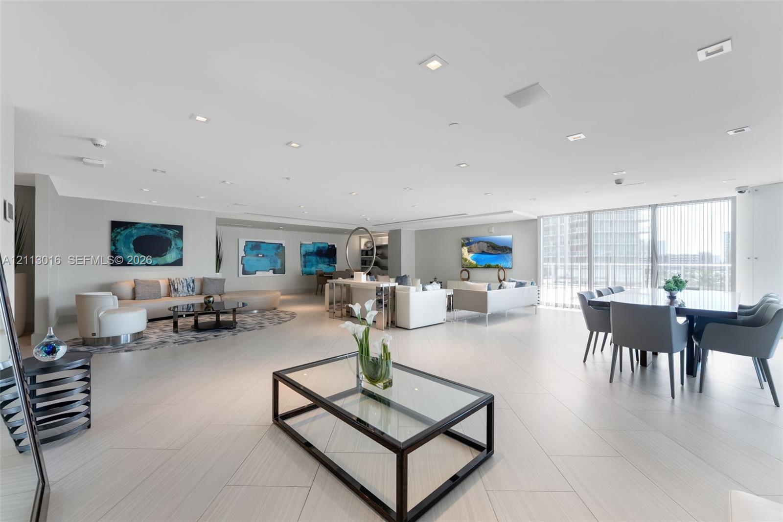 Open-concept interior featuring large-format tile flooring, recessed ceiling lighting, and floor-to-ceiling windows