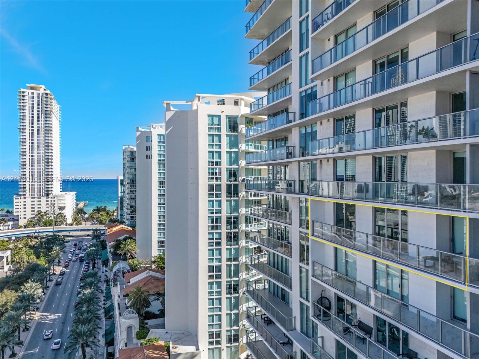 High-rise exterior featuring expansive glass-panel balconies, floor-to-ceiling windows, and a prominent coastal location