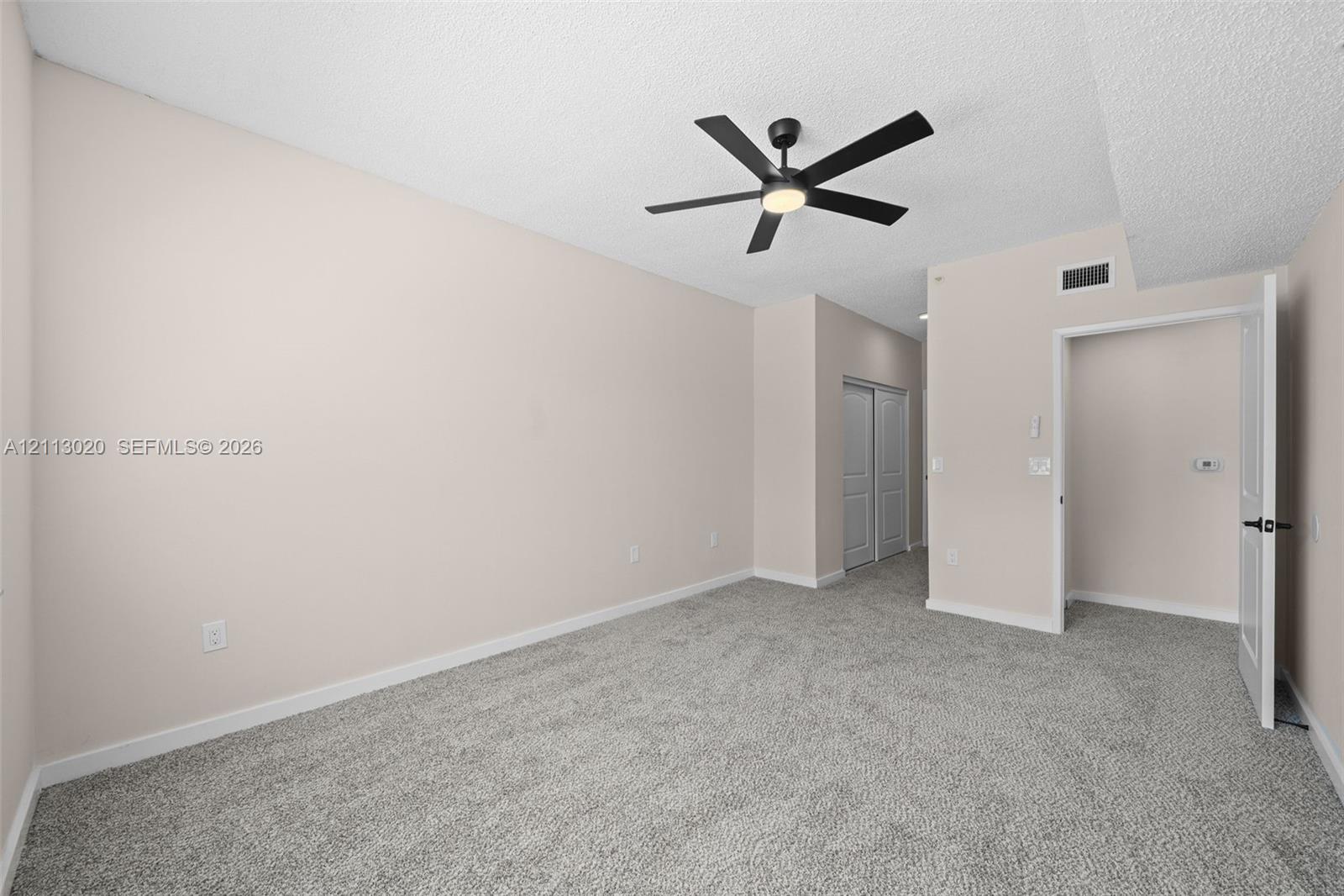 Neutral wall paint, ceiling fan with integrated lighting, wall-to-wall carpeting, and dual-panel closet doors