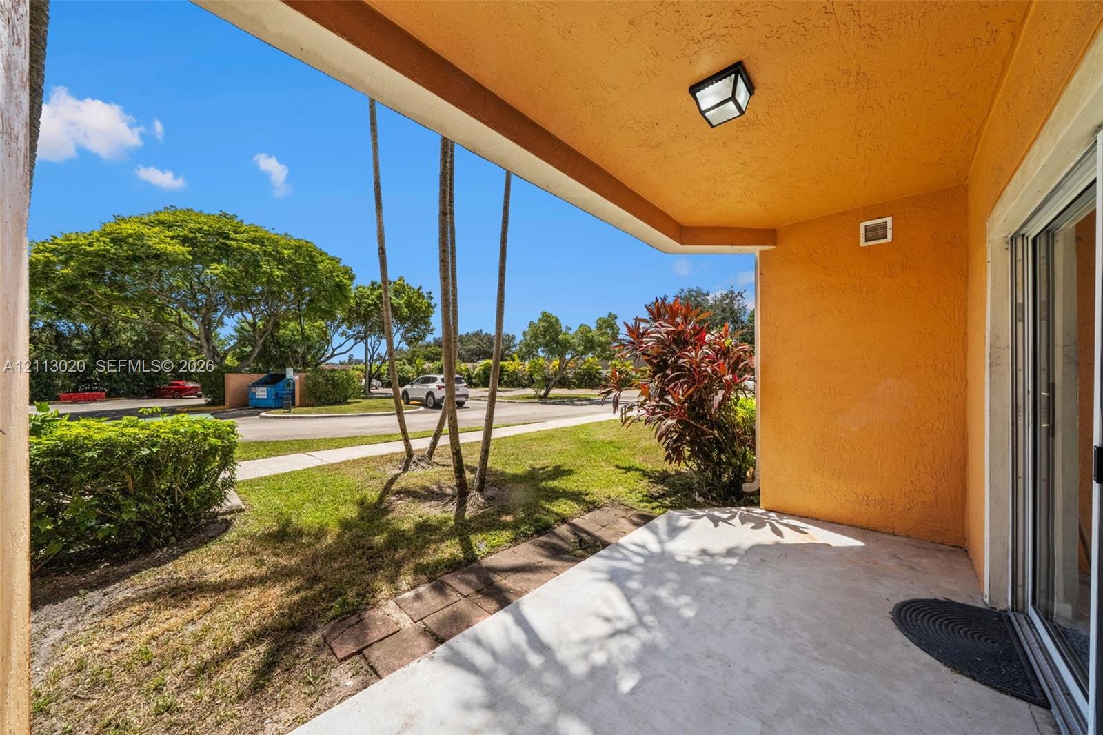 Covered concrete patio featuring a stucco ceiling, flush-mount lighting, and sliding glass door entry