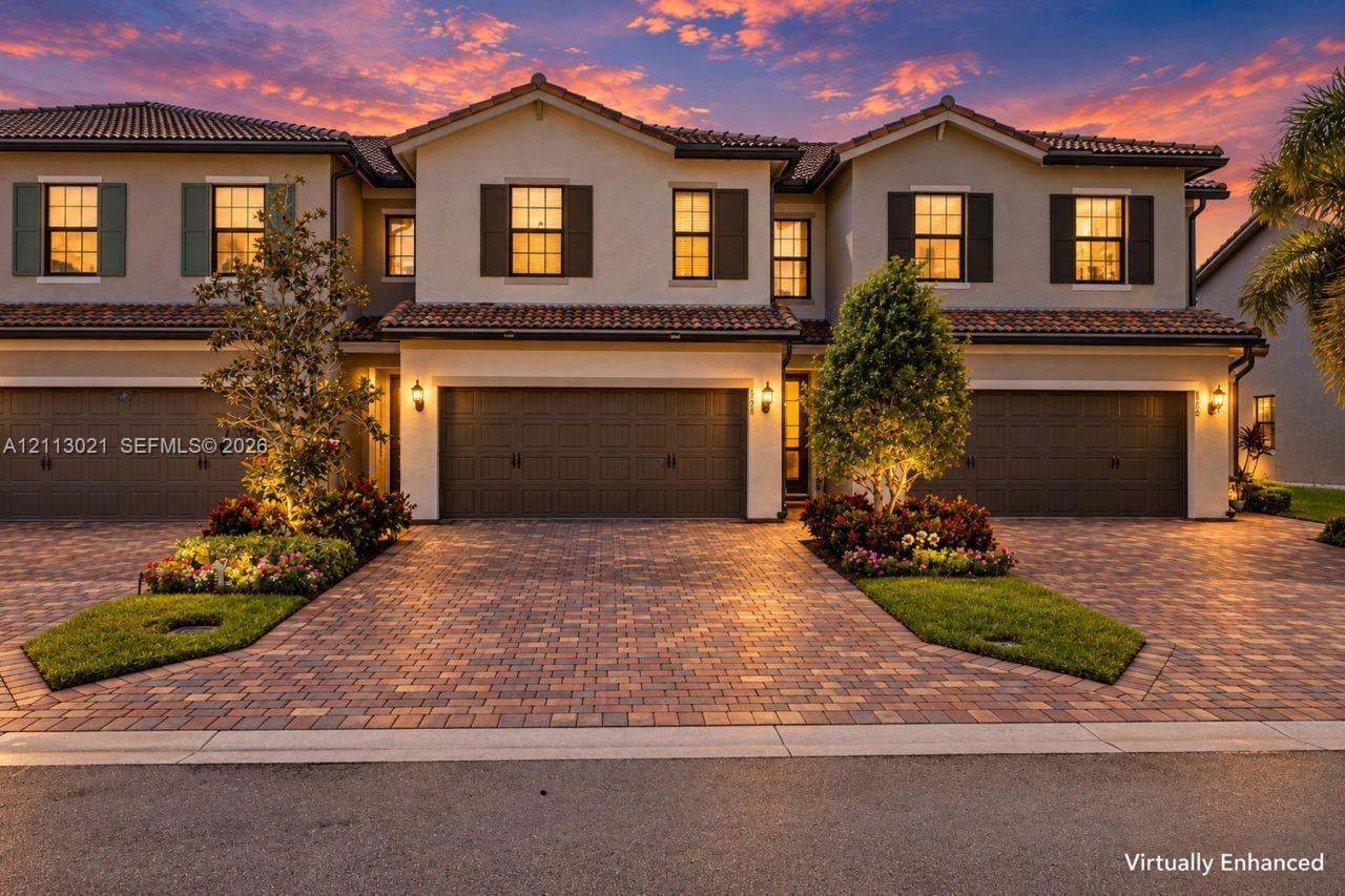 Stucco exterior featuring decorative shutters, clay tile roof, paver driveway, and landscaped garden beds Stucco exterior featuring decorative shutters, clay tile roof, paver driveway, and landscaped garden beds