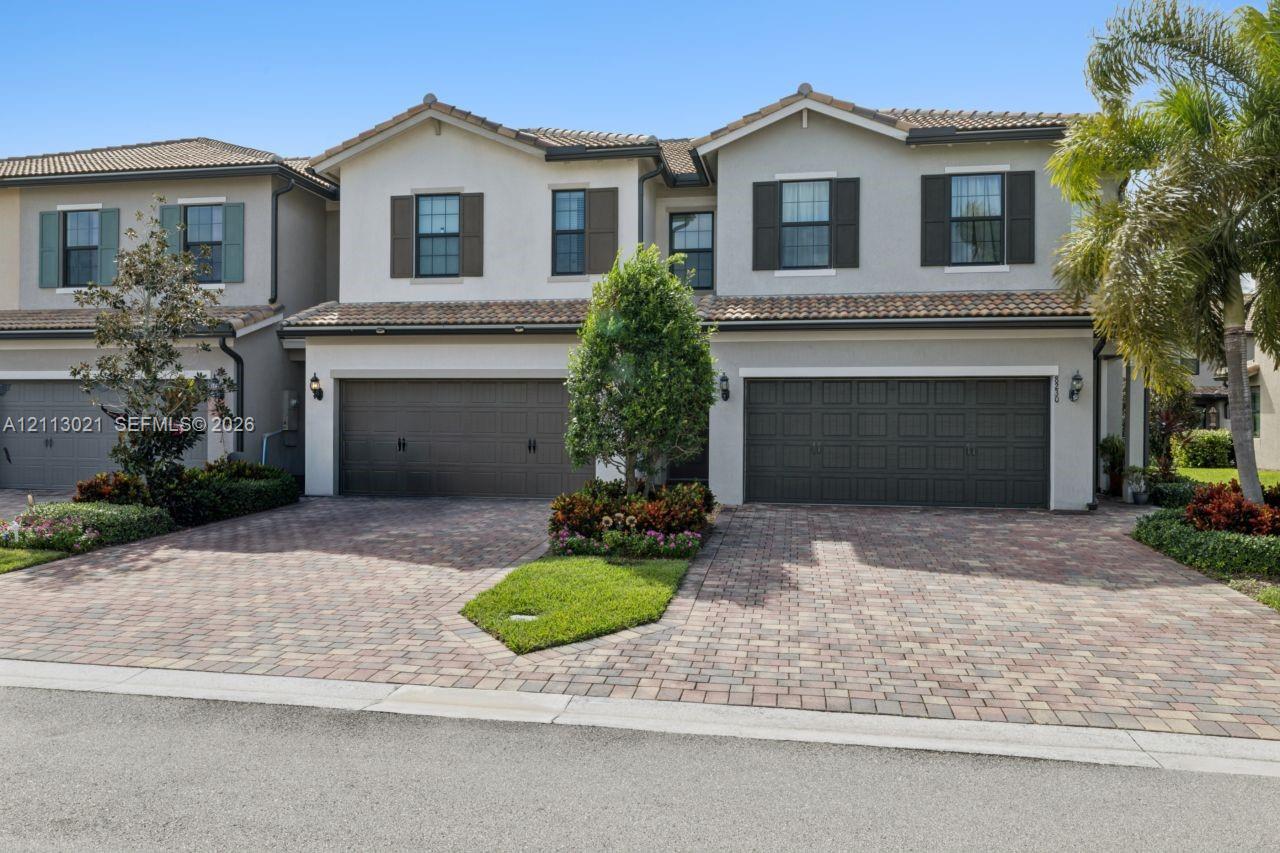 Stucco exterior featuring dual multi-car garages, decorative shutters, tile roofing, and a paved driveway Stucco exterior featuring dual multi-car garages, decorative shutters, tile roofing, and a paved driveway