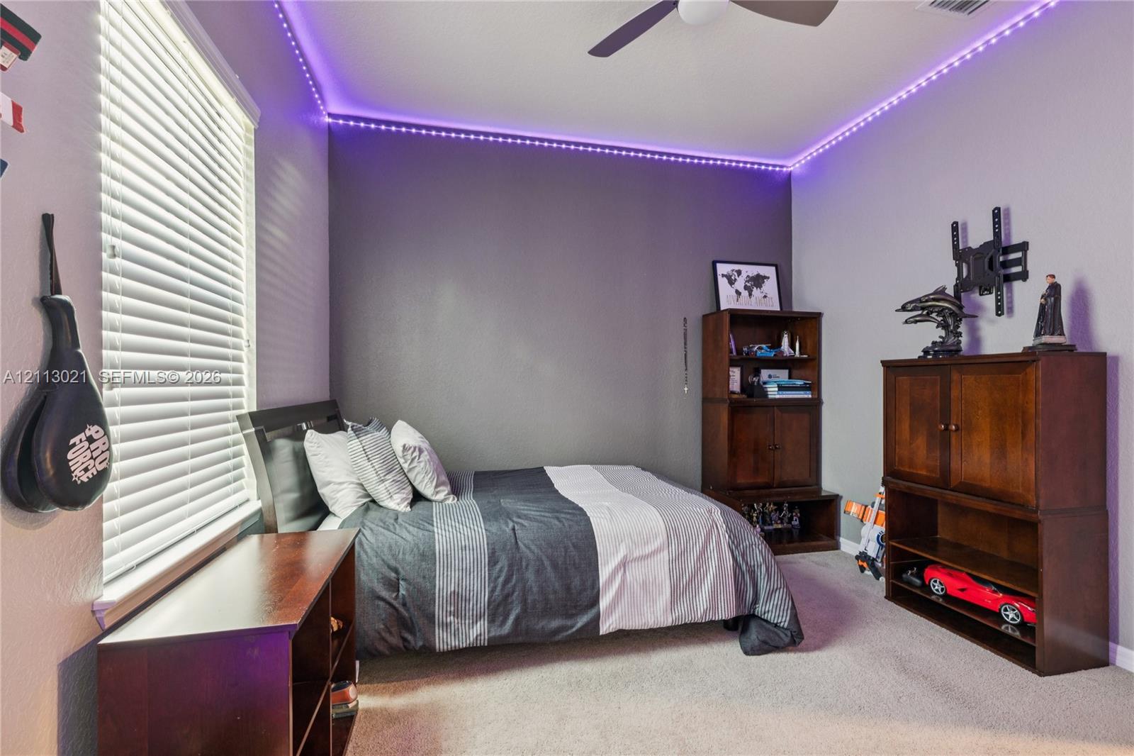 Room featuring neutral carpeting, horizontal window blinds, and a ceiling fan with integrated lighting