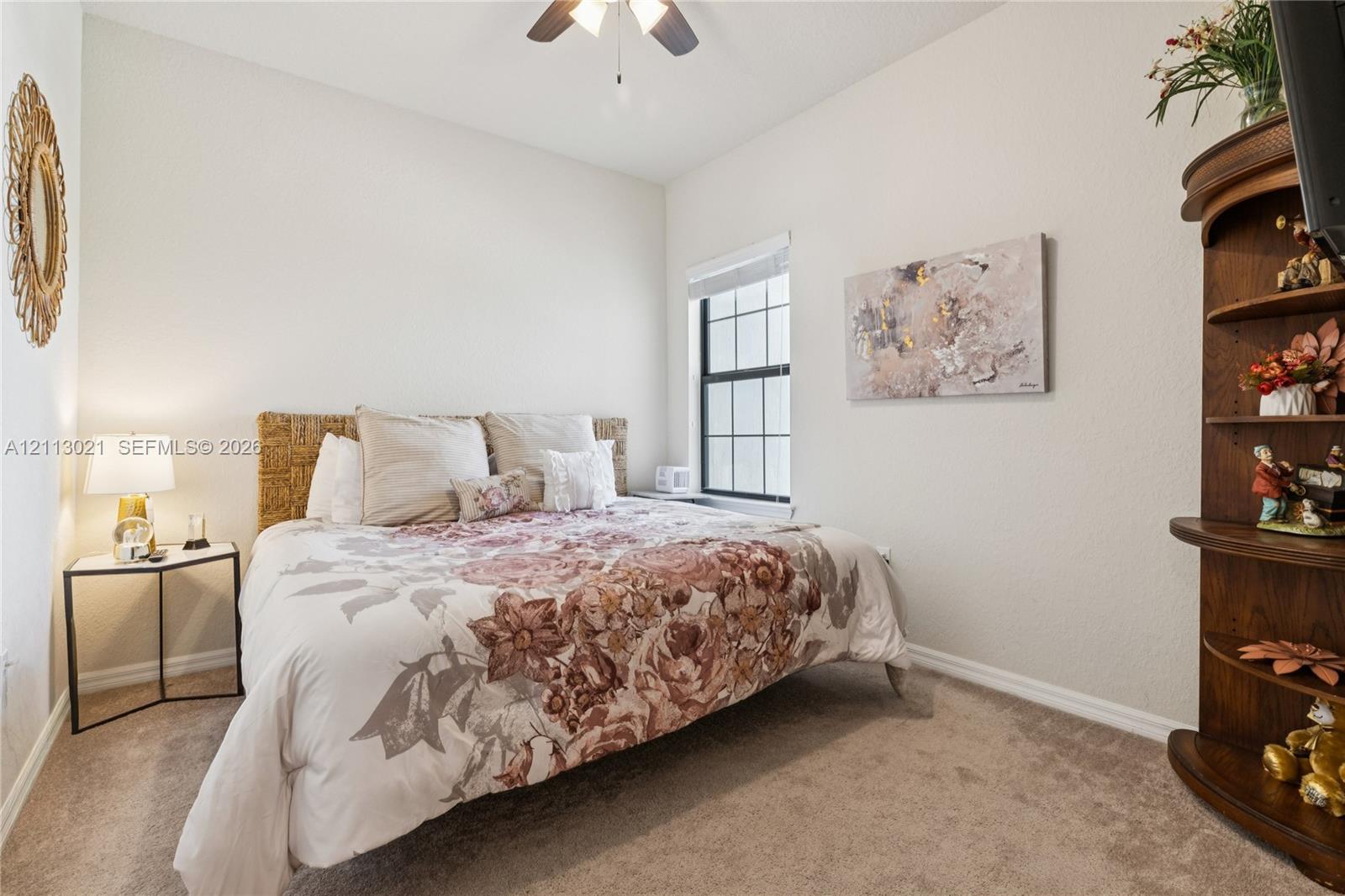 Neutral-toned interior space featuring neutral wall-to-wall carpeting, a single-hung window with white framing, and a ceiling-mounted fan fixture