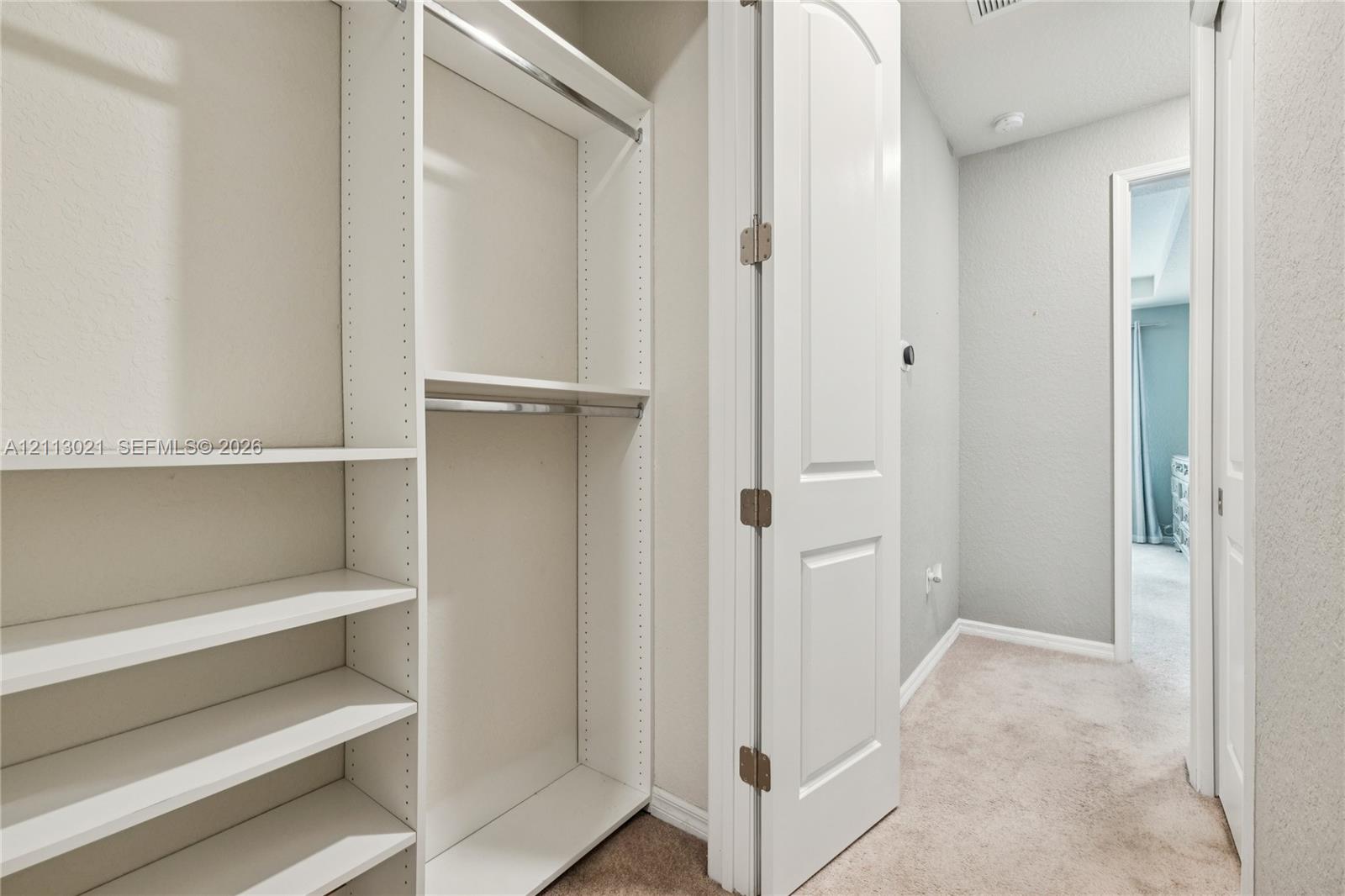 Built-in white storage shelving, dual hanging rods, and a solid-core interior door