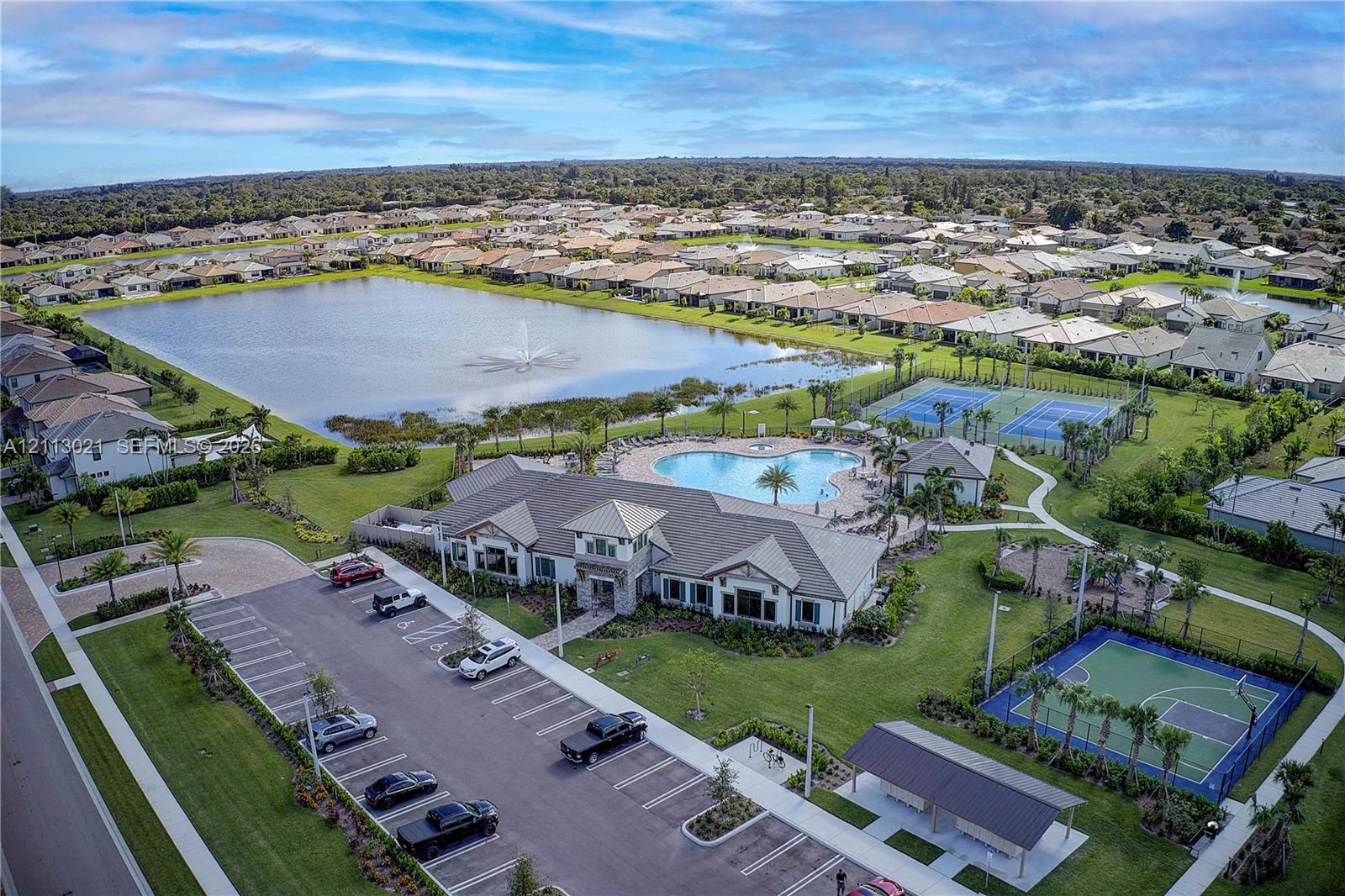Community center complex featuring a swimming pool with fountain, tennis courts, basketball court, and a multi-acre lake with fountain