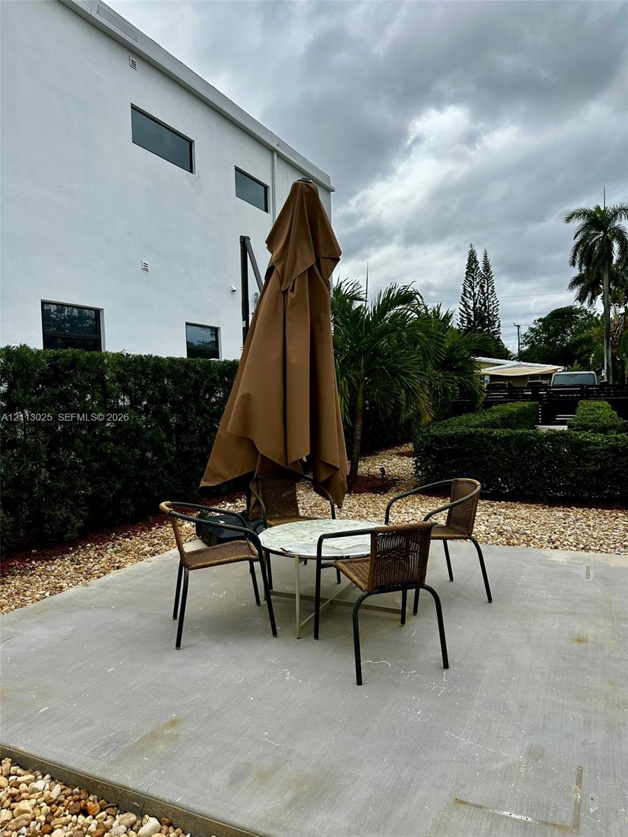 Concrete patio featuring professional landscaping with manicured hedges and stone ground cover