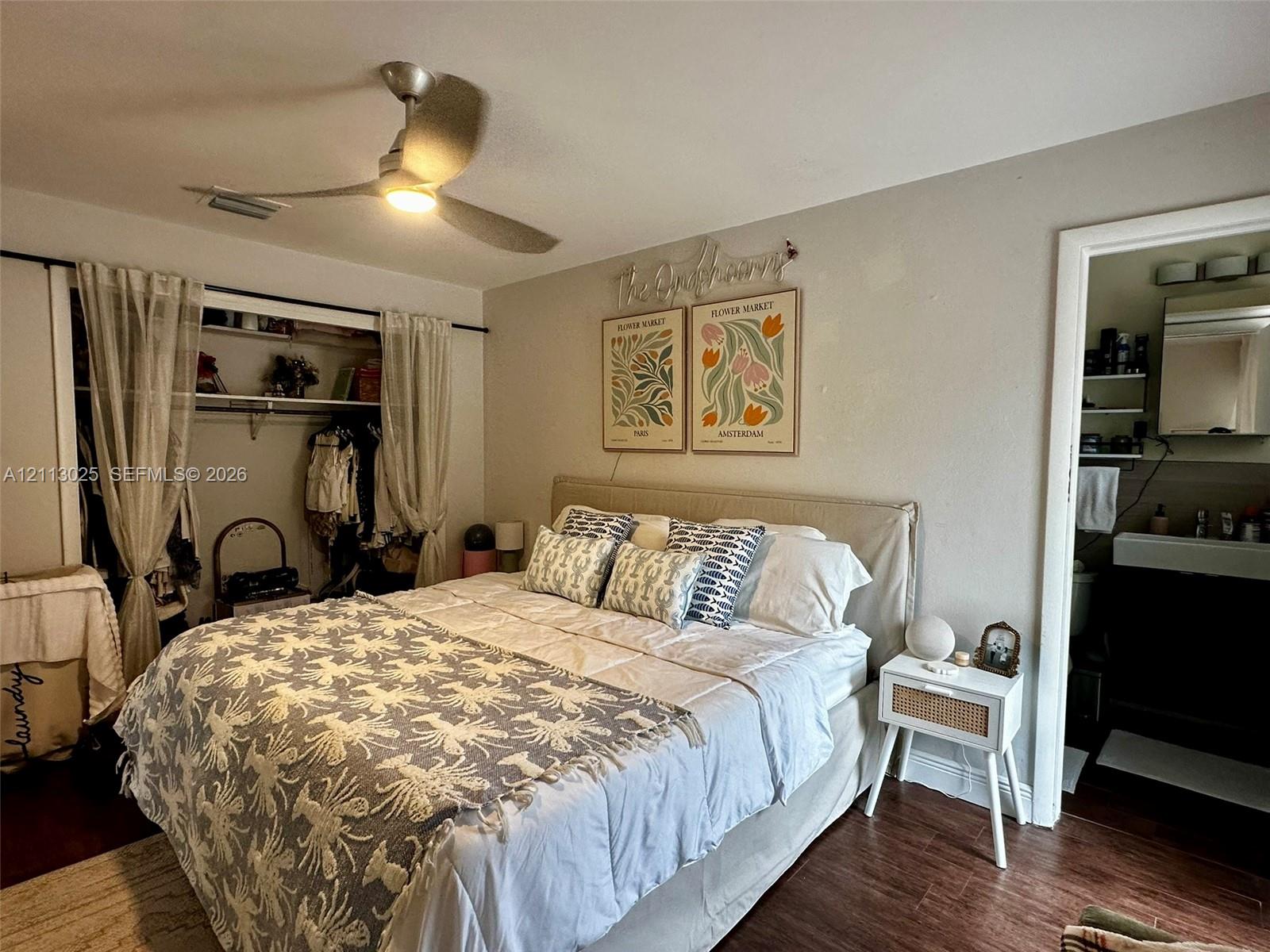 Bedroom featuring wood-finish flooring, a ceiling fan with integrated lighting, and an open closet area with built-in shelving