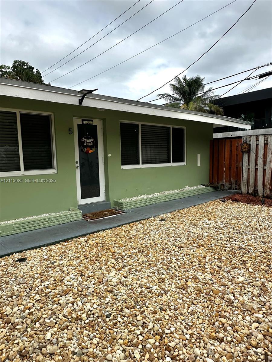 Exterior featuring a painted finish, low-slope roofline, concrete walkway, and gravel yard area