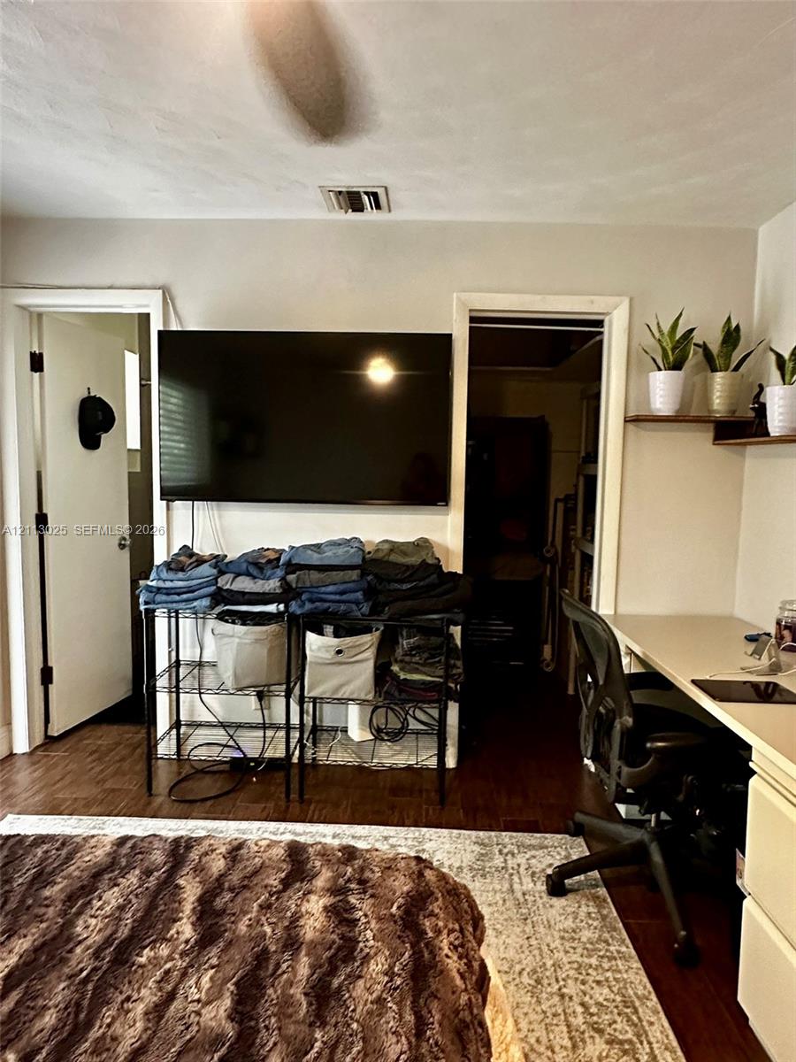 Interior room featuring wood-finish flooring, two wooden wall-mounted shelves, and a built-in desk surface