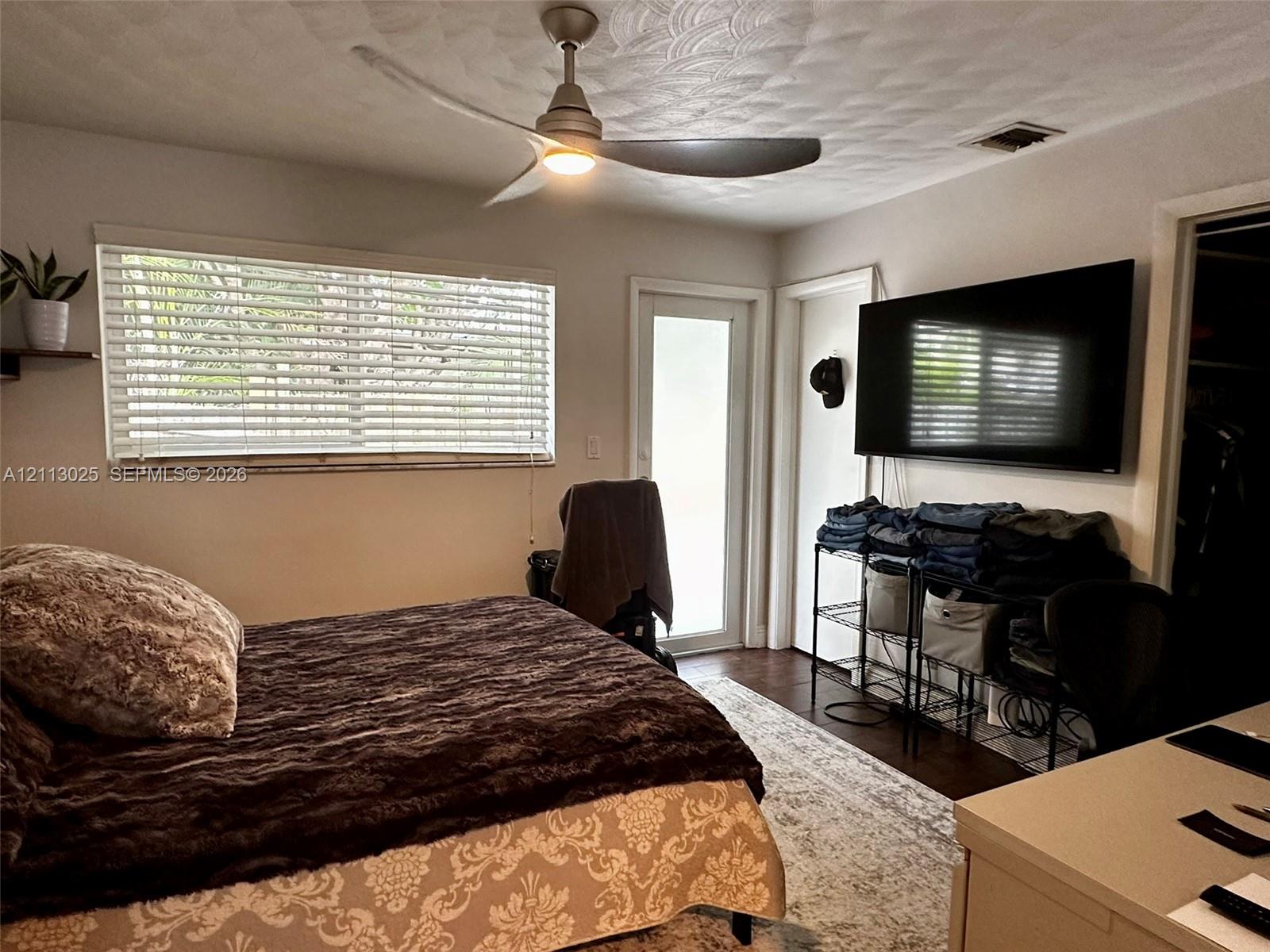 Room featuring a matte finish ceiling fan with integrated lighting, horizontal window blinds, and a glass-paneled exterior door