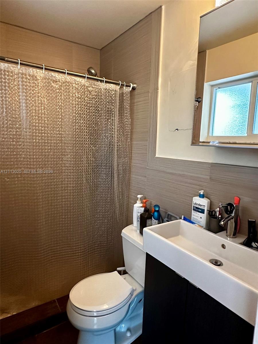 Bathroom featuring horizontal-patterned tile wall surrounds, a modern dark-finish vanity with a rectangular sink, a polished metal faucet, and a wall-mounted rectangular mirror