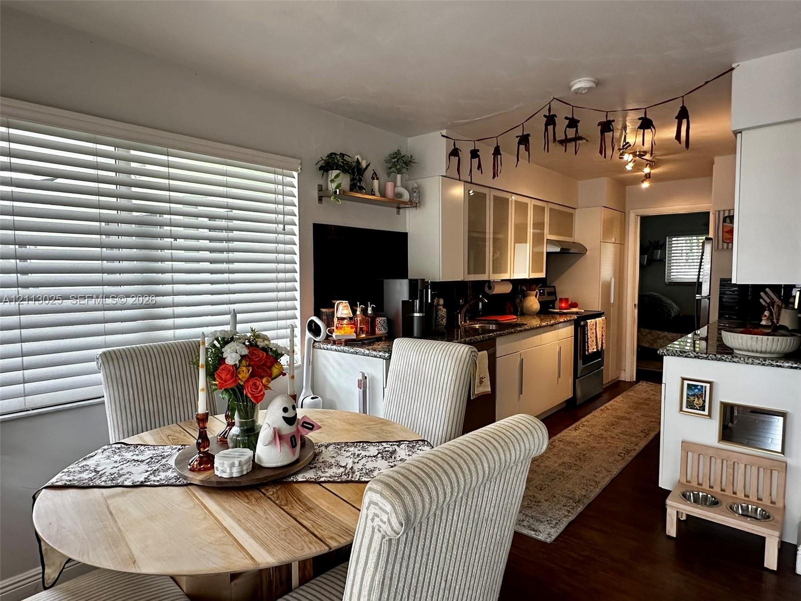Kitchen featuring white shaker-style cabinetry, stone-finish countertops, glass-front upper cabinets, and dark wood-finish flooring