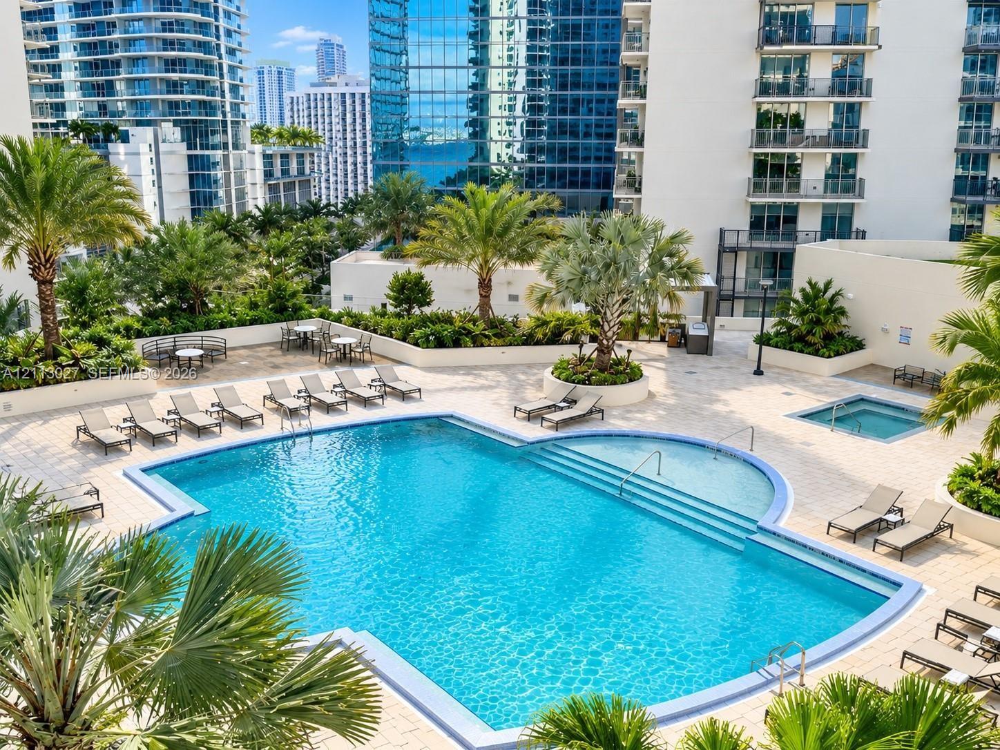 Swimming pool with integrated steps, raised spa, stone-paver pool deck, and mature palm landscaping