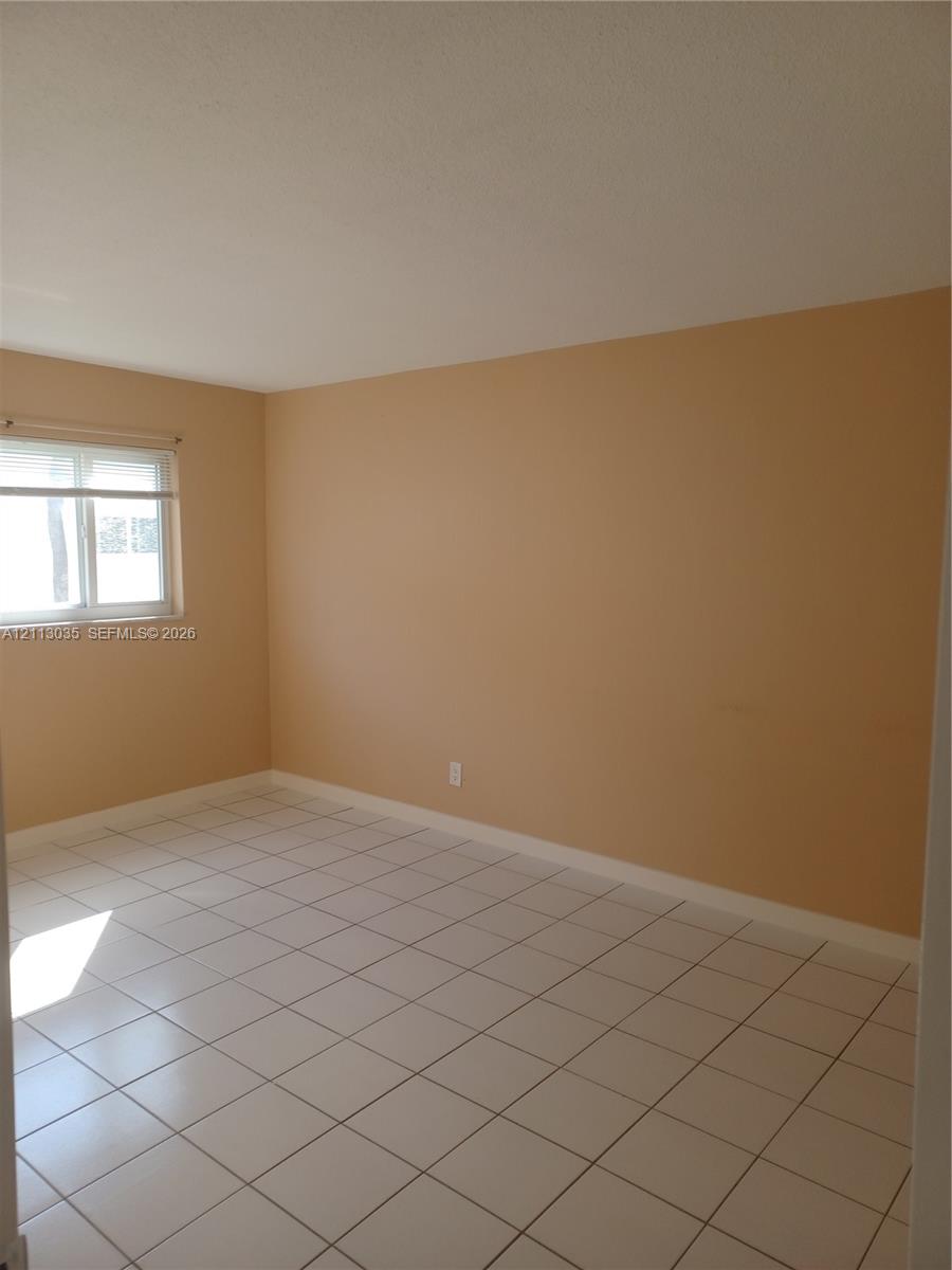 Room interior featuring neutral wall paint, square ceramic tile flooring, and a single-pane horizontal sliding window