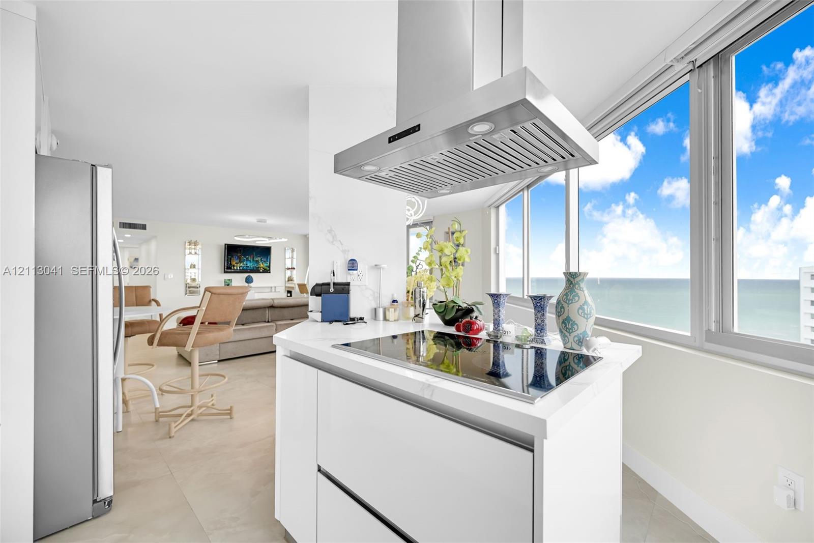 Kitchen featuring white cabinetry, solid-surface countertop, stainless steel range hood, built-in cooktop, and floor-to-ceiling windows