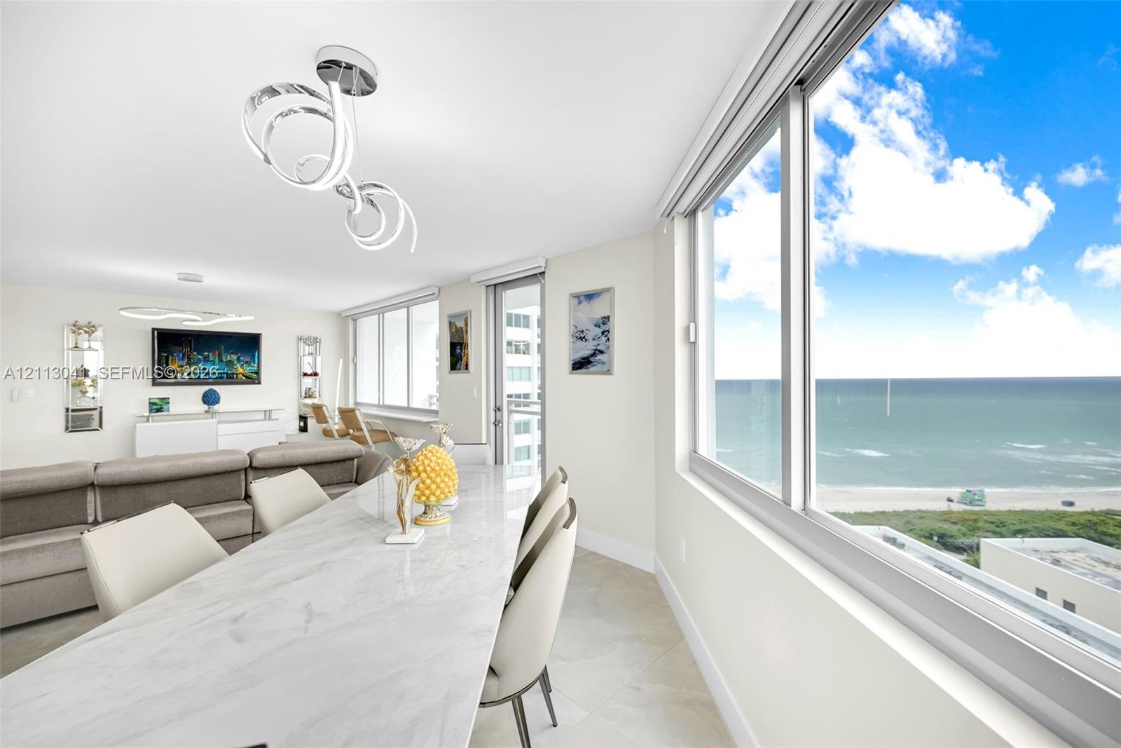 Open-concept living space featuring floor-to-ceiling windows, polished stone flooring, modern LED circular light fixtures, and expansive ocean scenery Open-concept living space featuring floor-to-ceiling windows, polished stone flooring, modern LED circular light fixtures, and expansive ocean scenery