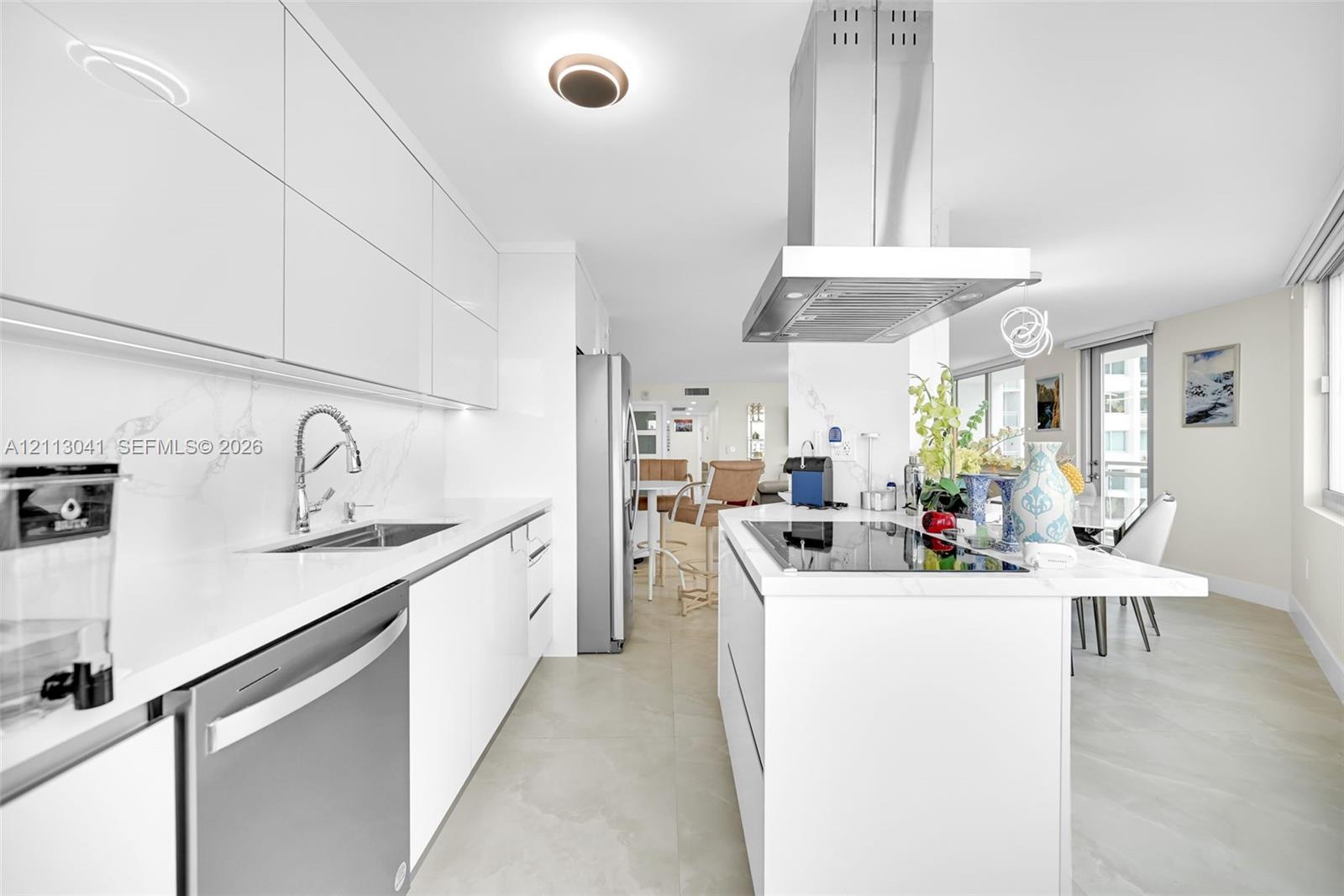 Sleek kitchen featuring high-gloss cabinetry, stone-finish countertops, stainless steel appliances, a center island with a built-in cooktop, and an overhead stainless steel range hood