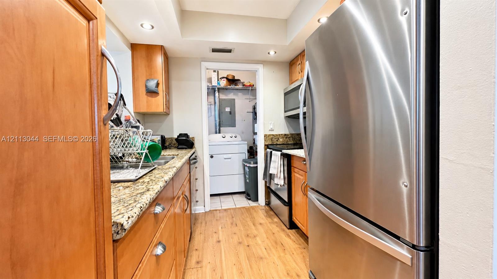 Kitchen featuring wood cabinetry, stone countertops, stainless steel appliances, recessed lighting, and wood-finish flooring