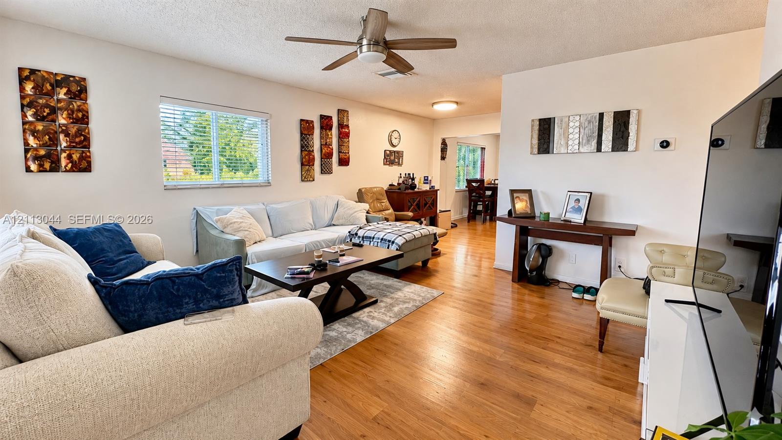 Wood-finish flooring, ceiling fan with integrated lighting, and horizontal window blinds
