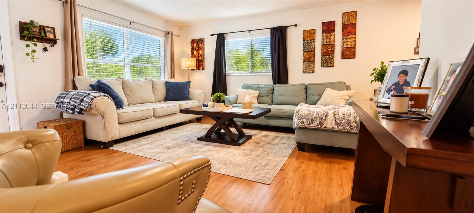 Living area featuring wood-finish flooring and dual windows with horizontal blinds