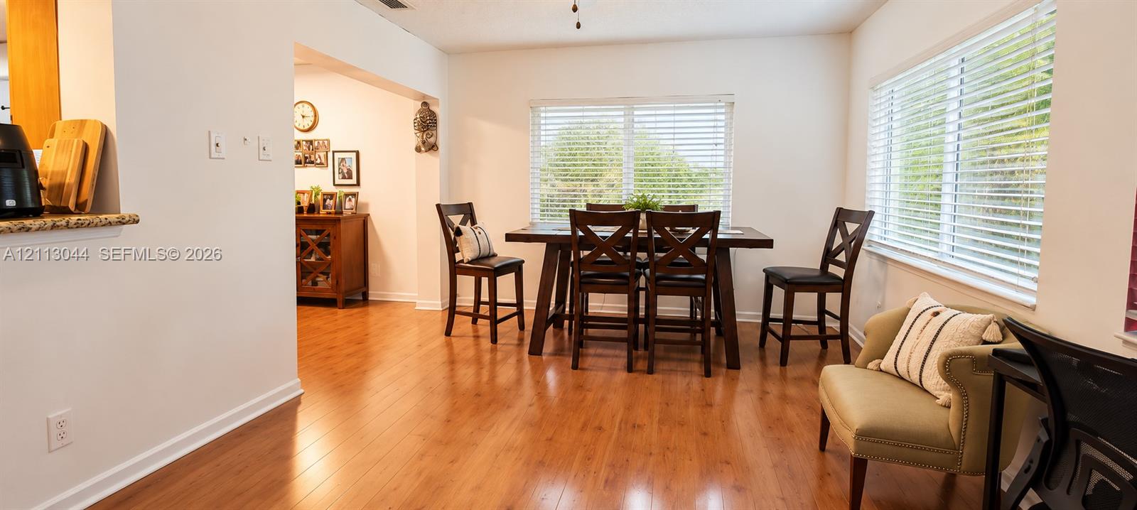 Open-concept dining area featuring wood-finish flooring, dual-aspect windows, and horizontal blinds
