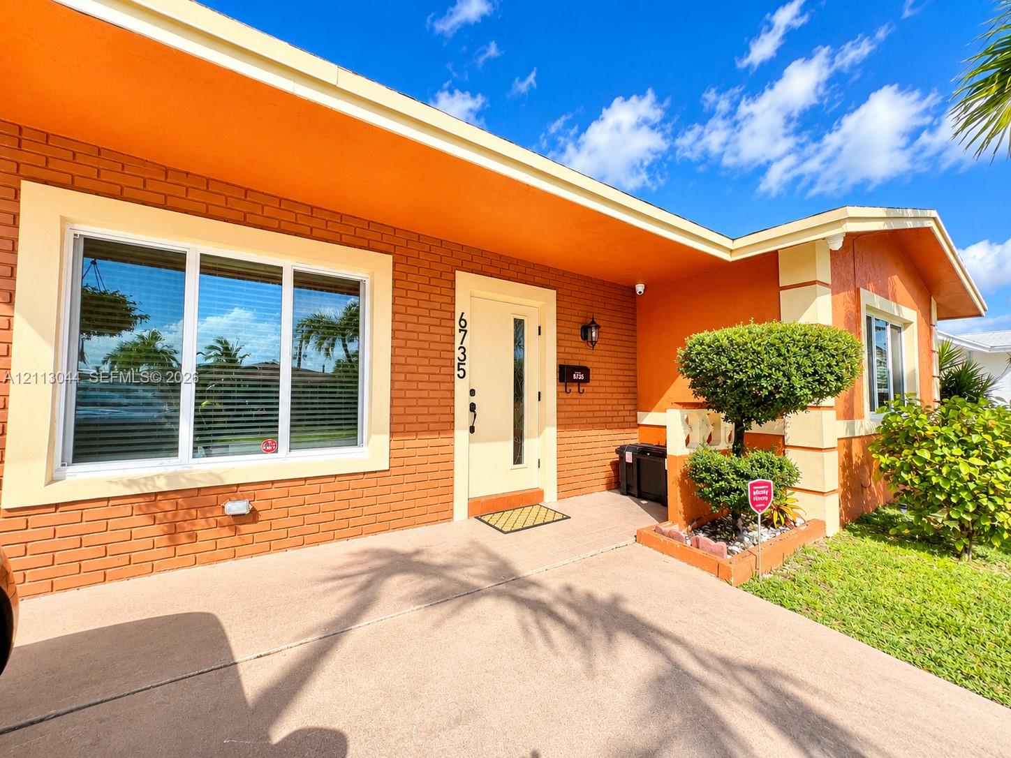 Mid-century inspired exterior featuring a brick facade, wide roof overhangs, custom trim detailing, a multi-pane front window, and a modern entry door with an integrated vertical glass panel