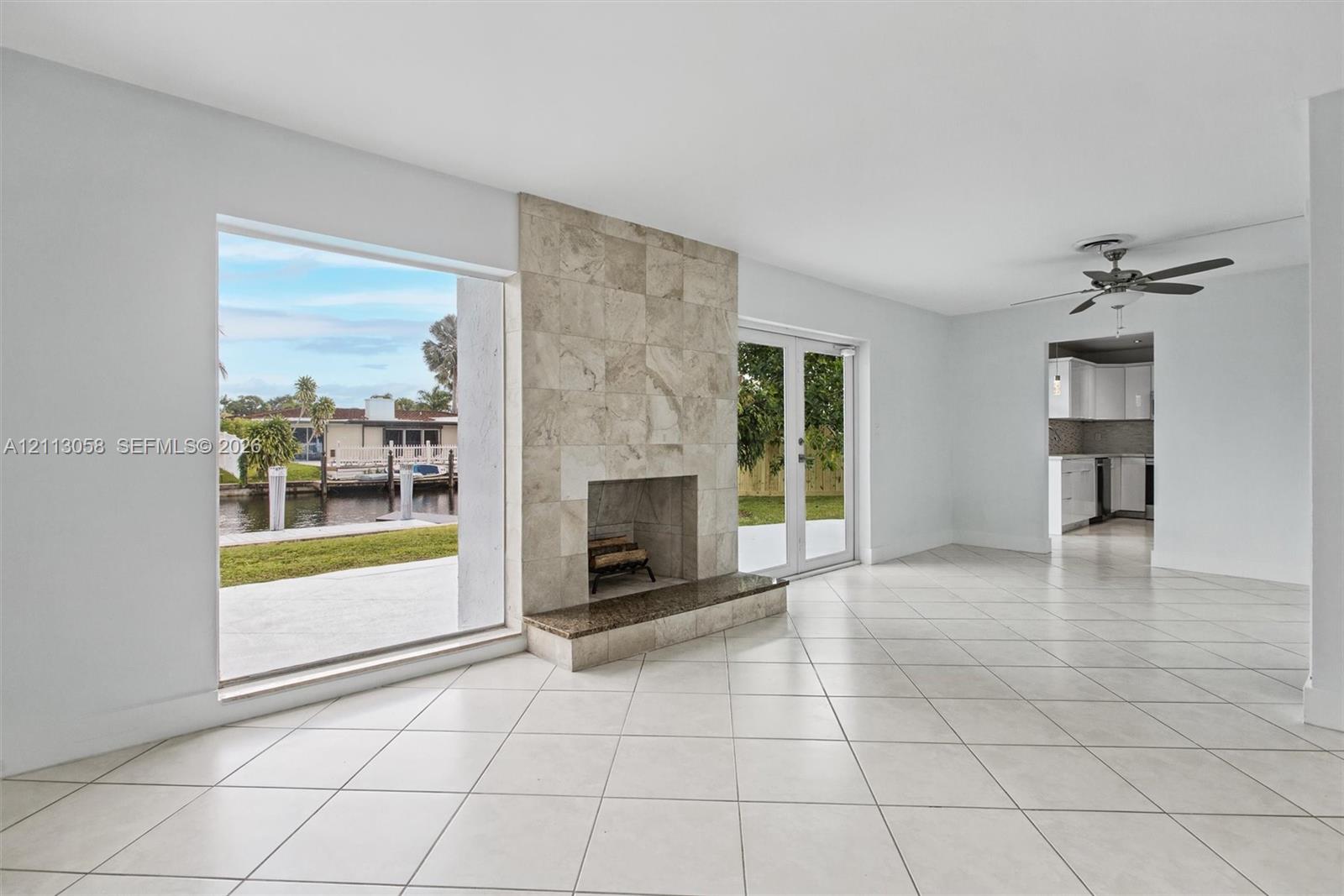 Living area featuring large-format tile flooring, a floor-to-ceiling fireplace with stone tile surround, a built-in stone hearth, and double glass doors