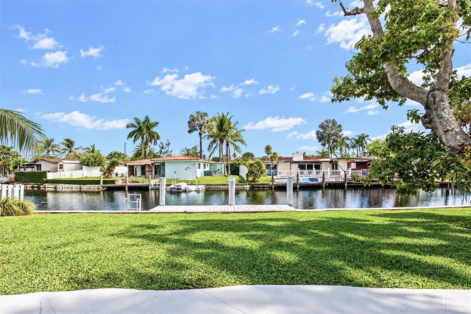Waterfront lot featuring a manicured lawn, concrete seawall, and private dock