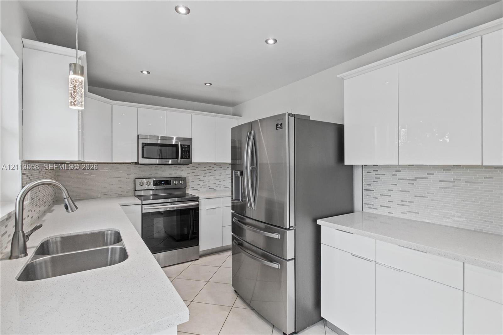 Kitchen featuring white slab-front cabinetry, stone-finish countertops, stainless steel appliances, a mosaic tile backsplash, and recessed ceiling lighting