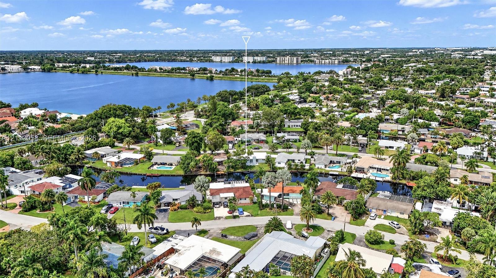 Aerial perspective featuring waterfront placement along a canal with mature landscaping and proximity to a large inland lake