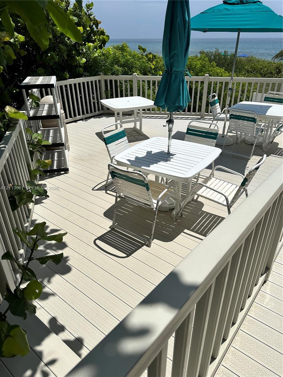 Elevated deck featuring composite plank flooring, white vertical balustrade railing, and an expansive ocean backdrop