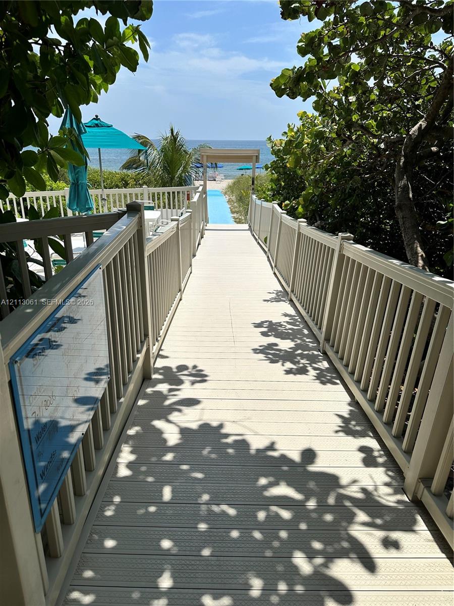 Elevated wooden boardwalk featuring perimeter railings and a covered entry archway leading to the beach