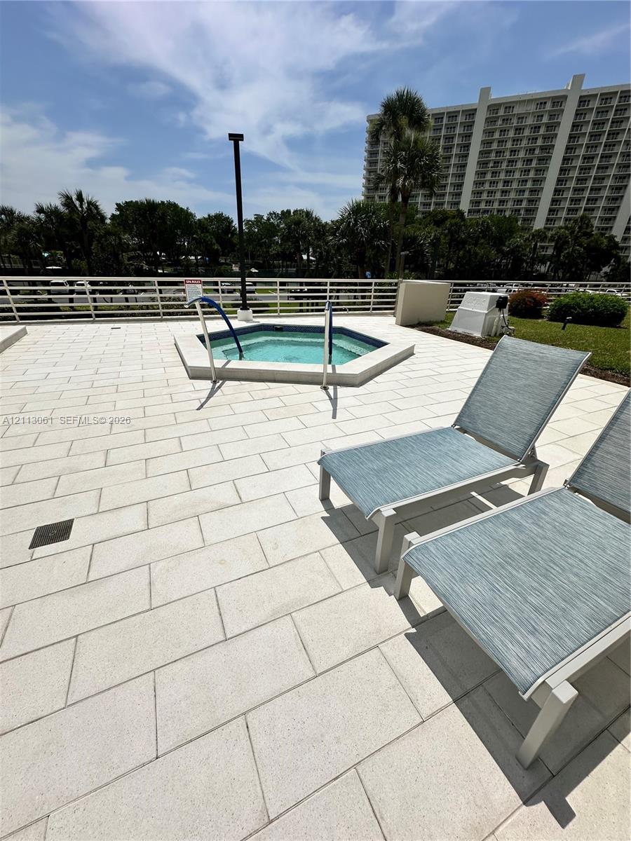 Elevated terrace featuring a paved stone deck, an in-ground spa, and a perimeter safety railing