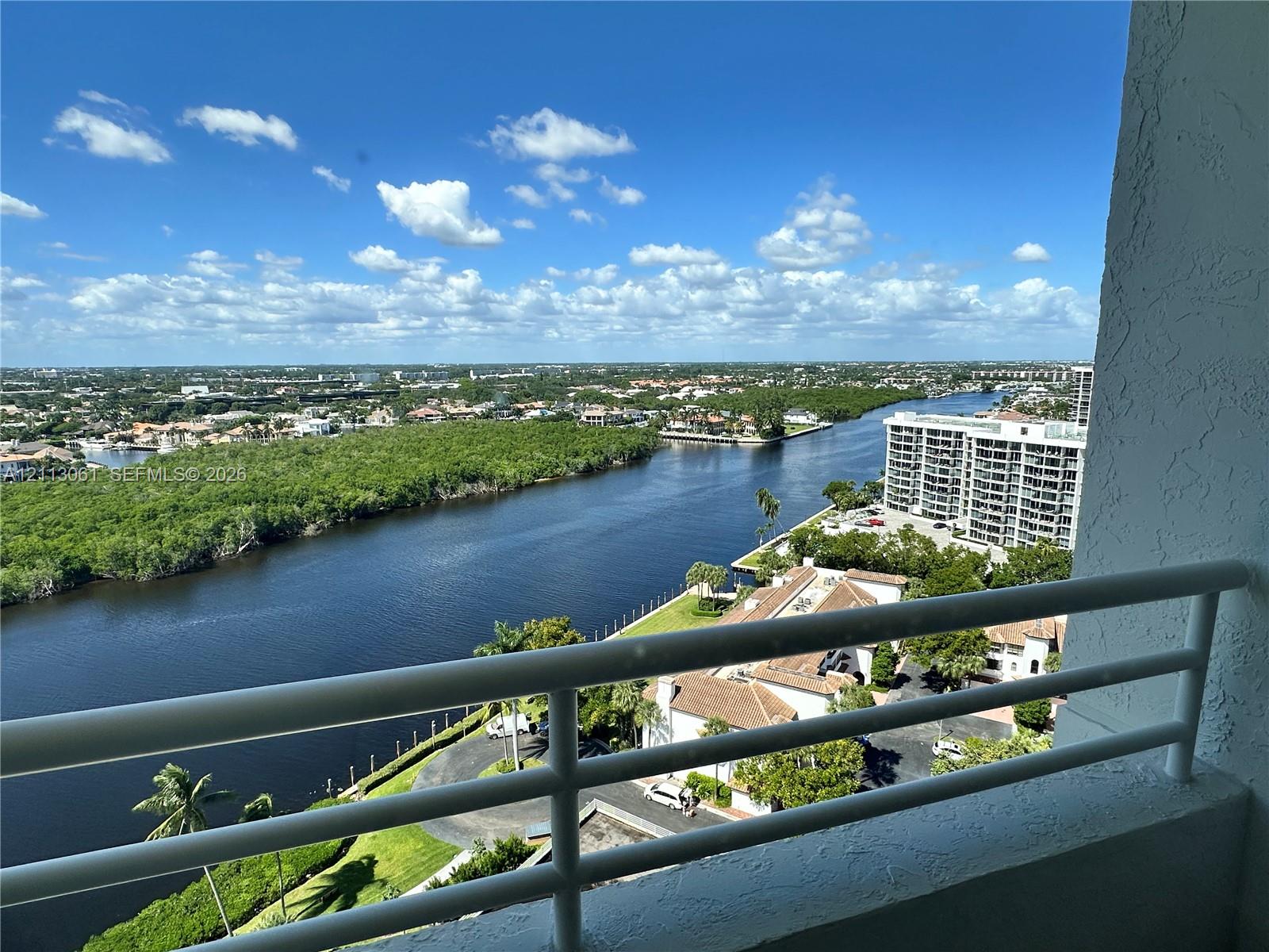 Private balcony featuring a white metal railing and a perspective of the waterway and surrounding landscape