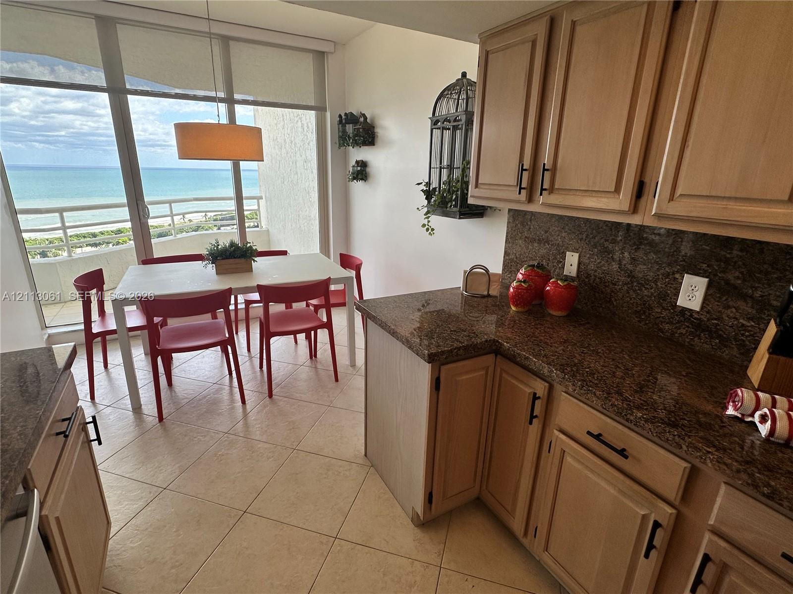 Kitchen featuring wood cabinetry, stone countertops, tiled flooring, pendant lighting, and floor-to-ceiling glass windows