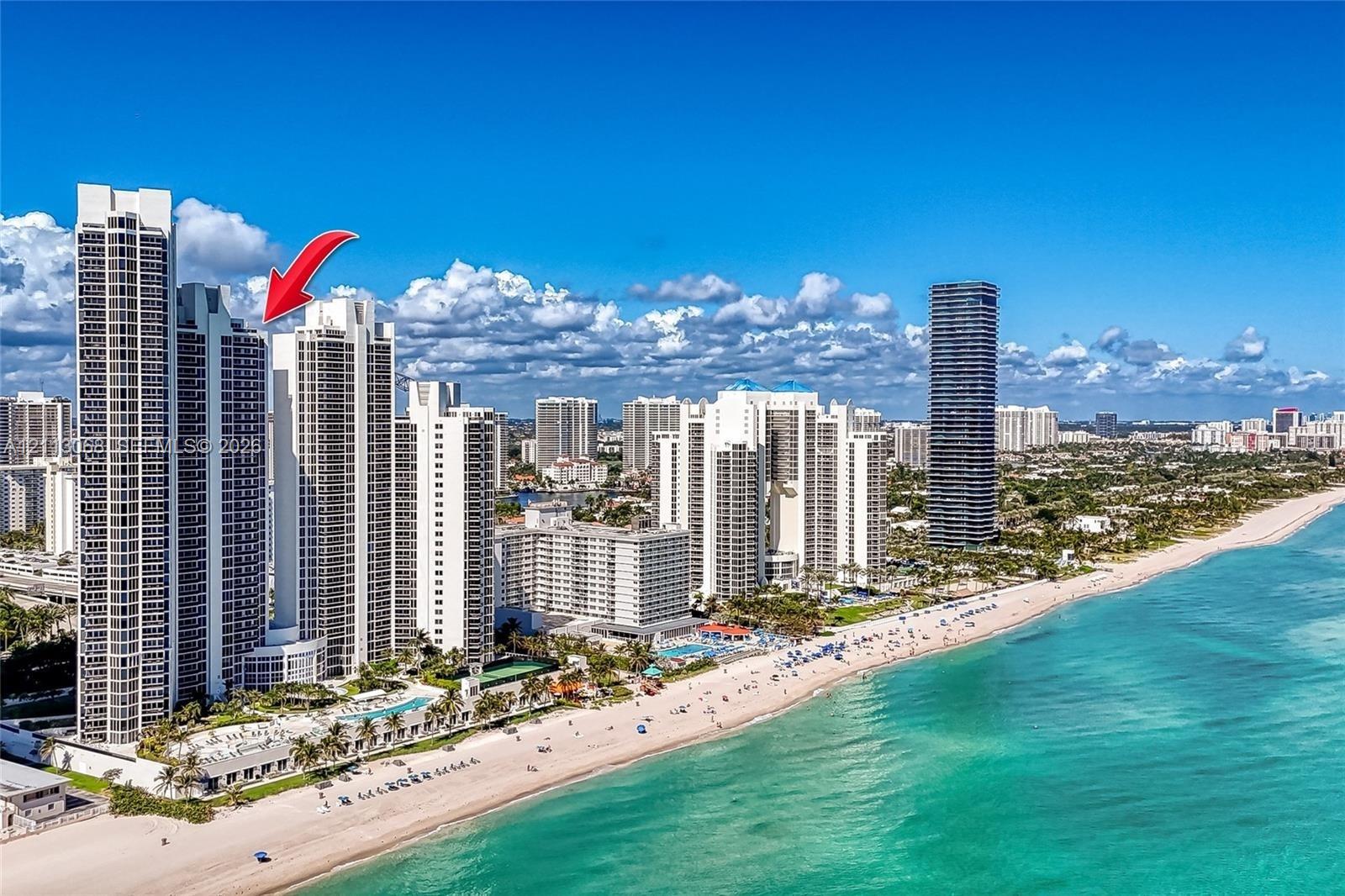 High-rise residential tower located directly on the coastline featuring extensive glass exterior cladding, proximity to the beach, and ground-level pool facilities High-rise residential tower located directly on the coastline featuring extensive glass exterior cladding, proximity to the beach, and ground-level pool facilities