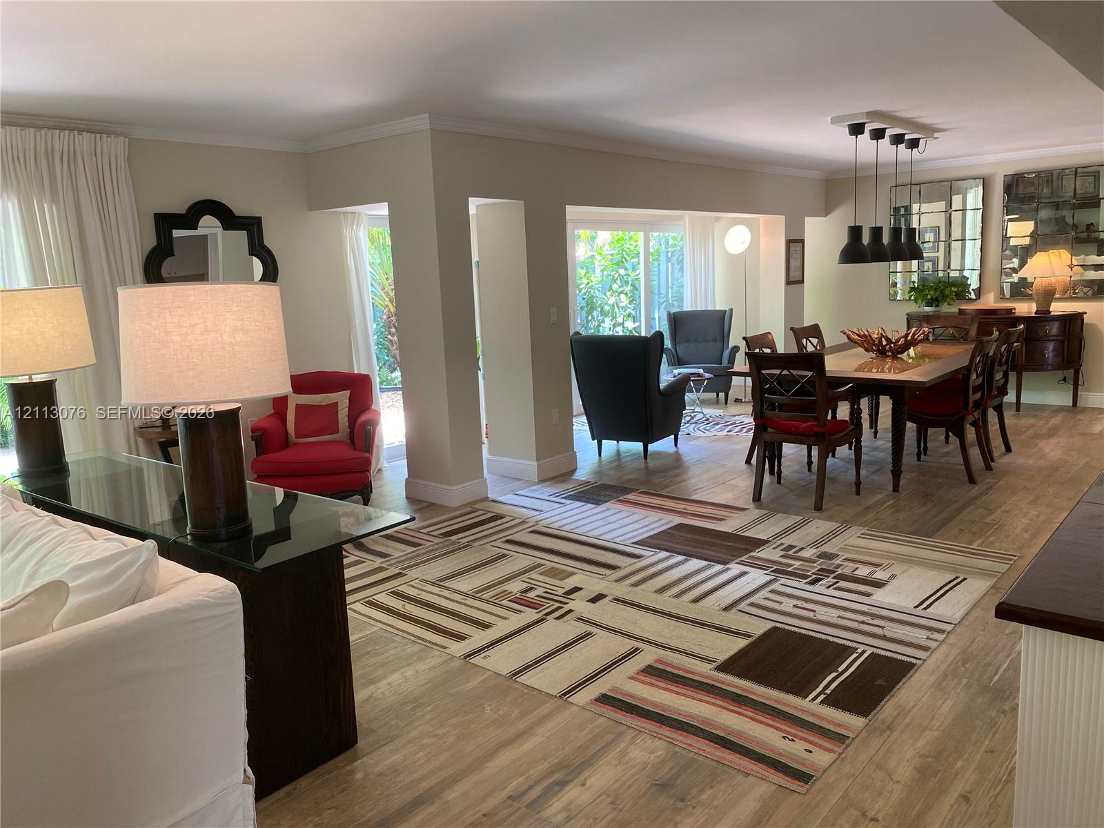 Open-concept interior featuring wood-finish flooring, crown molding, and a multi-pendant light fixture