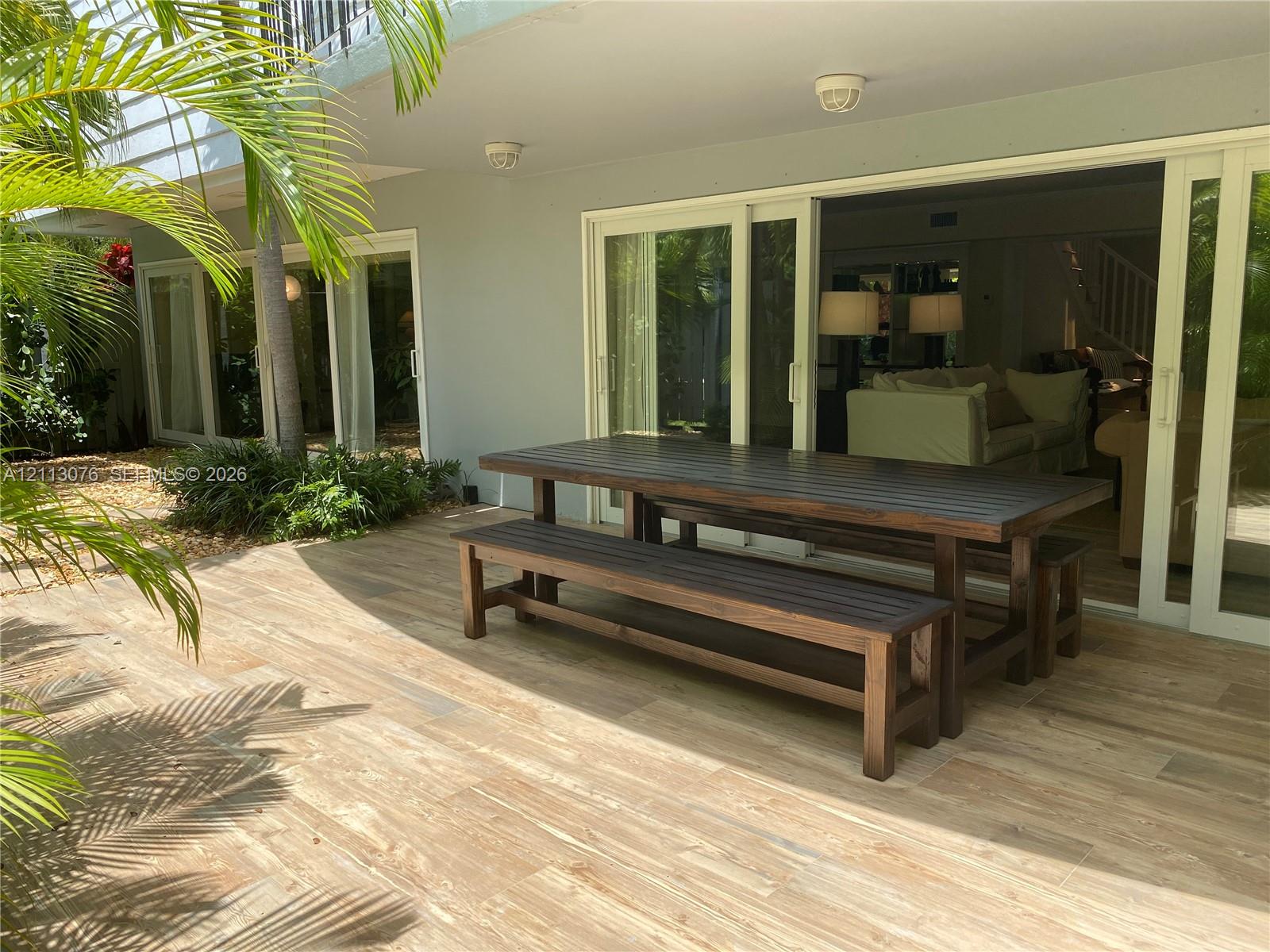Covered patio featuring wood-finish tile flooring, multiple sliding glass door sets, and recessed lighting