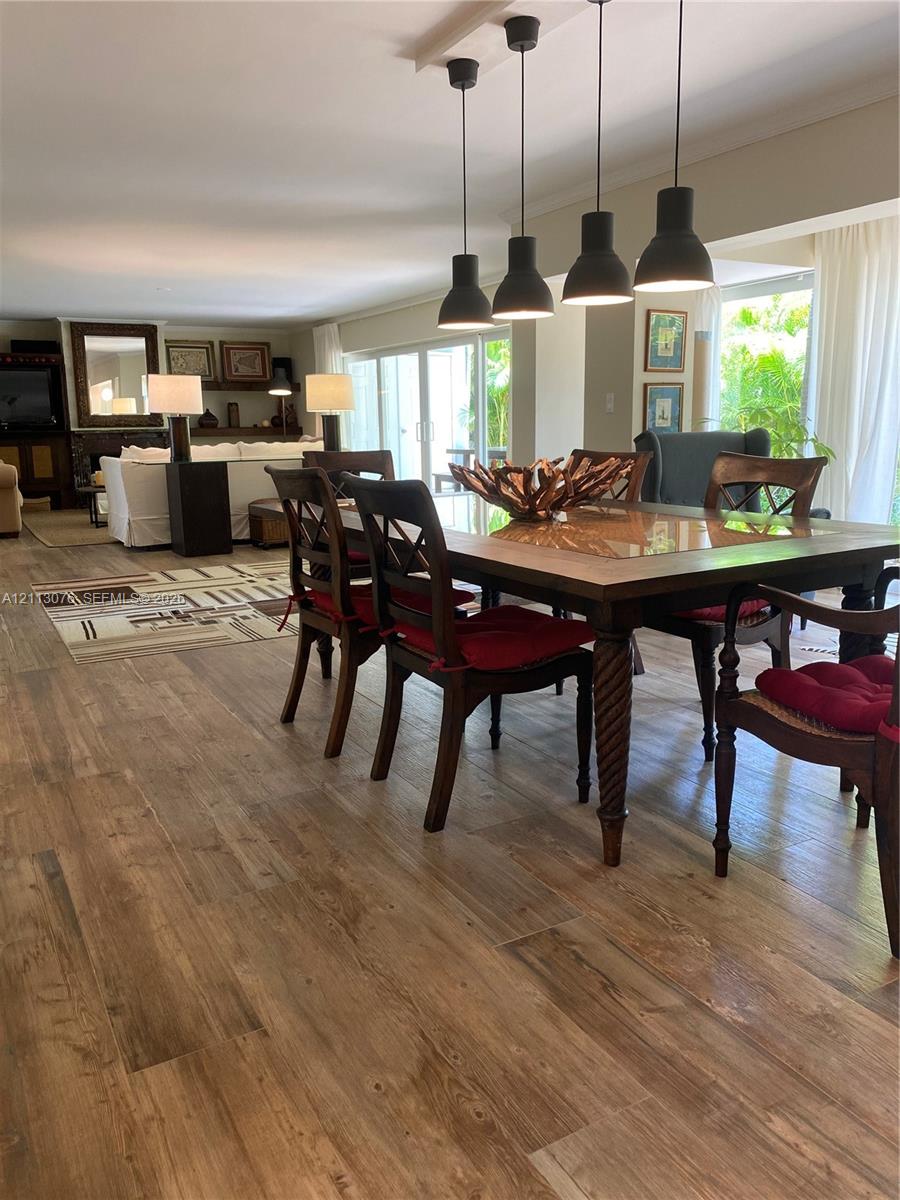 Open-concept living space featuring wood-finish flooring, four industrial-style pendant lights, and floor-to-ceiling sliding glass doors Open-concept living space featuring wood-finish flooring, four industrial-style pendant lights, and floor-to-ceiling sliding glass doors
