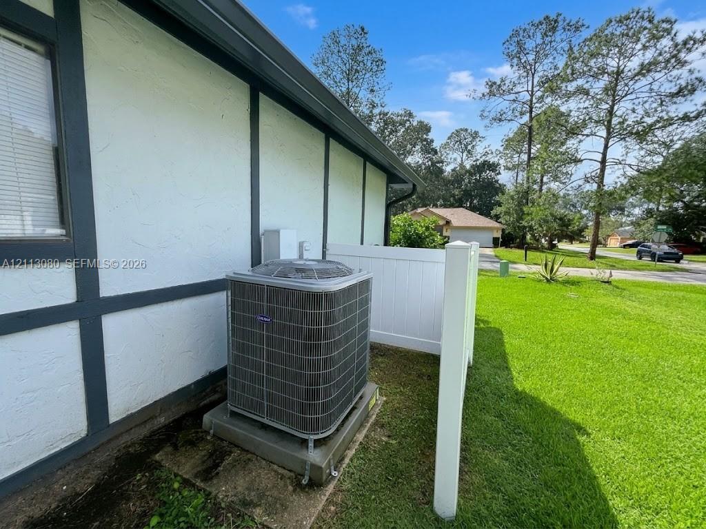 Exterior wall with stucco finish and dark wood-style trim, privacy screen fencing, and dedicated concrete equipment pad
