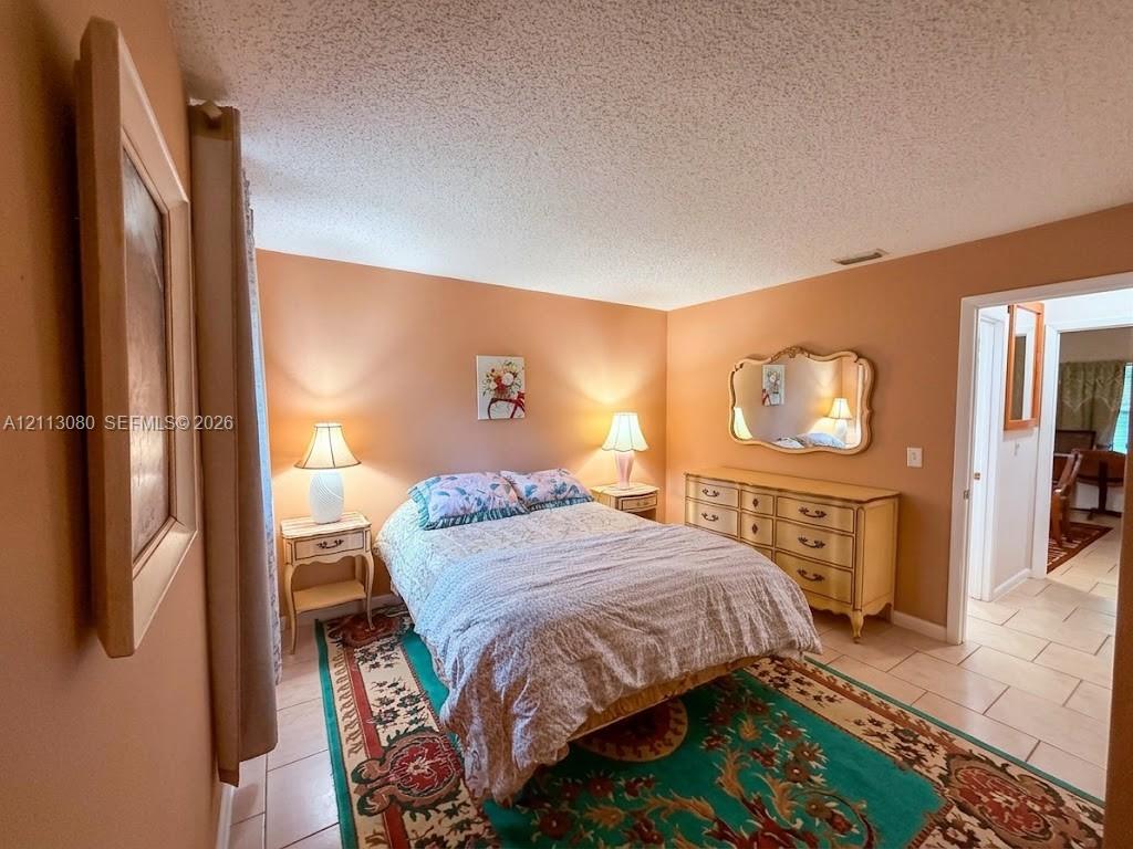 Neutral-toned interior space featuring light-colored ceramic tile flooring and textured ceiling finish