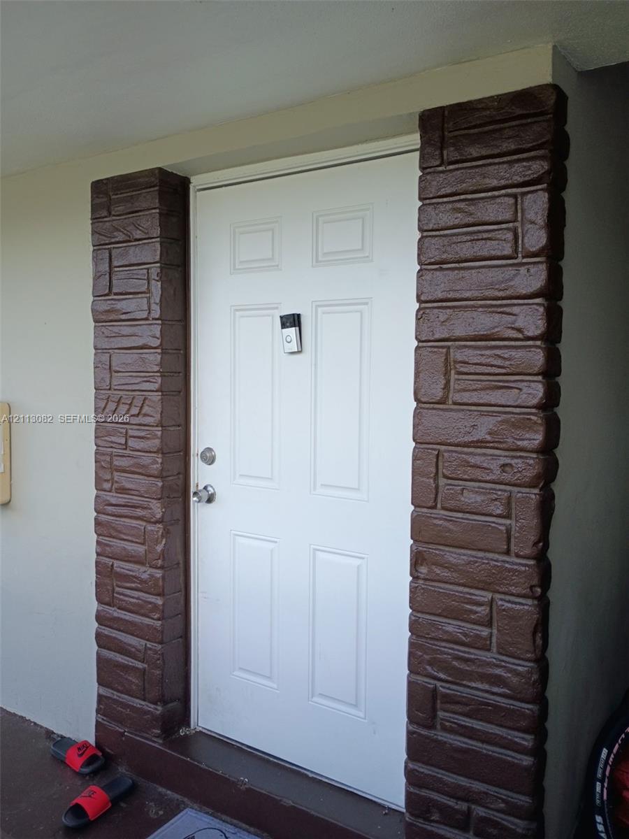 Entryway featuring a white paneled door framed by brown textured stone-veneer pillars